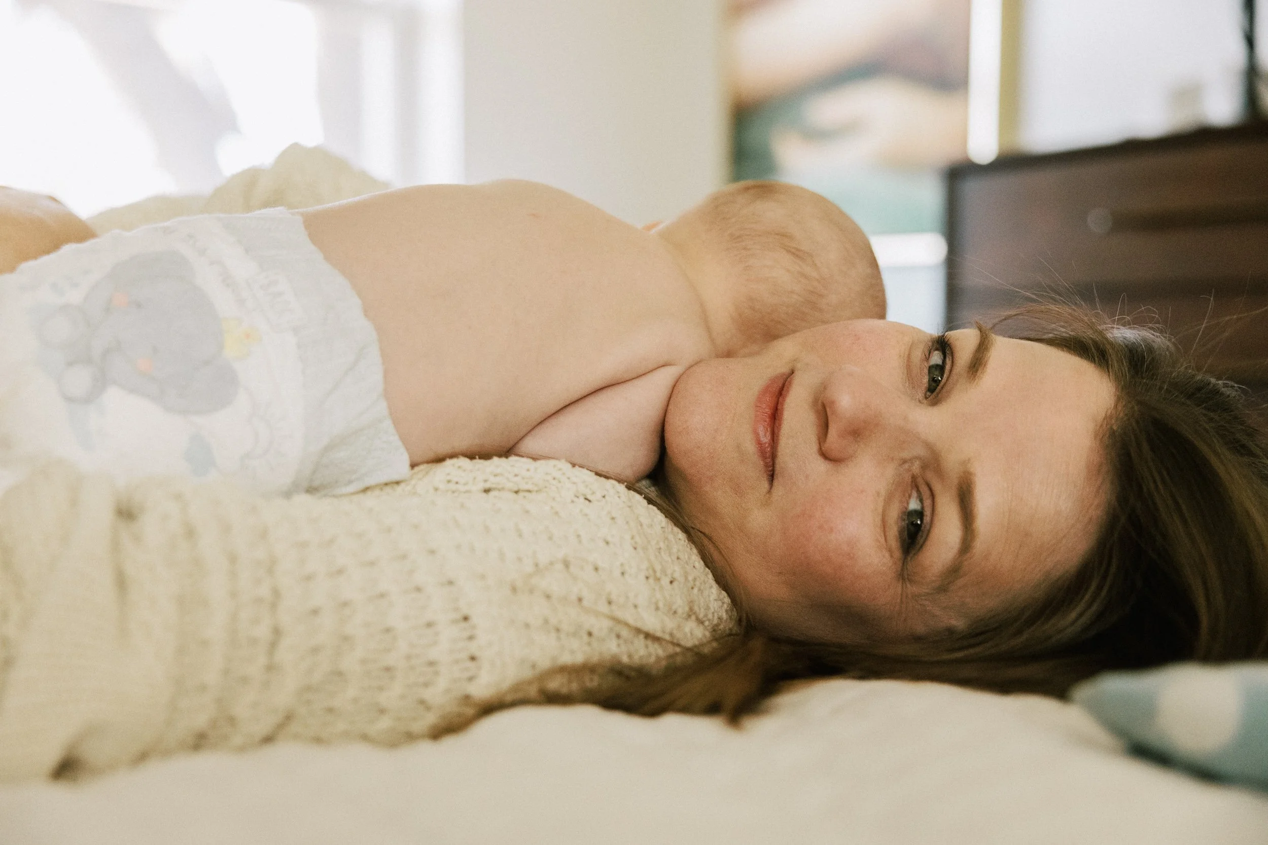 mom looks at camera while holding baby during newborn photos in seattle
