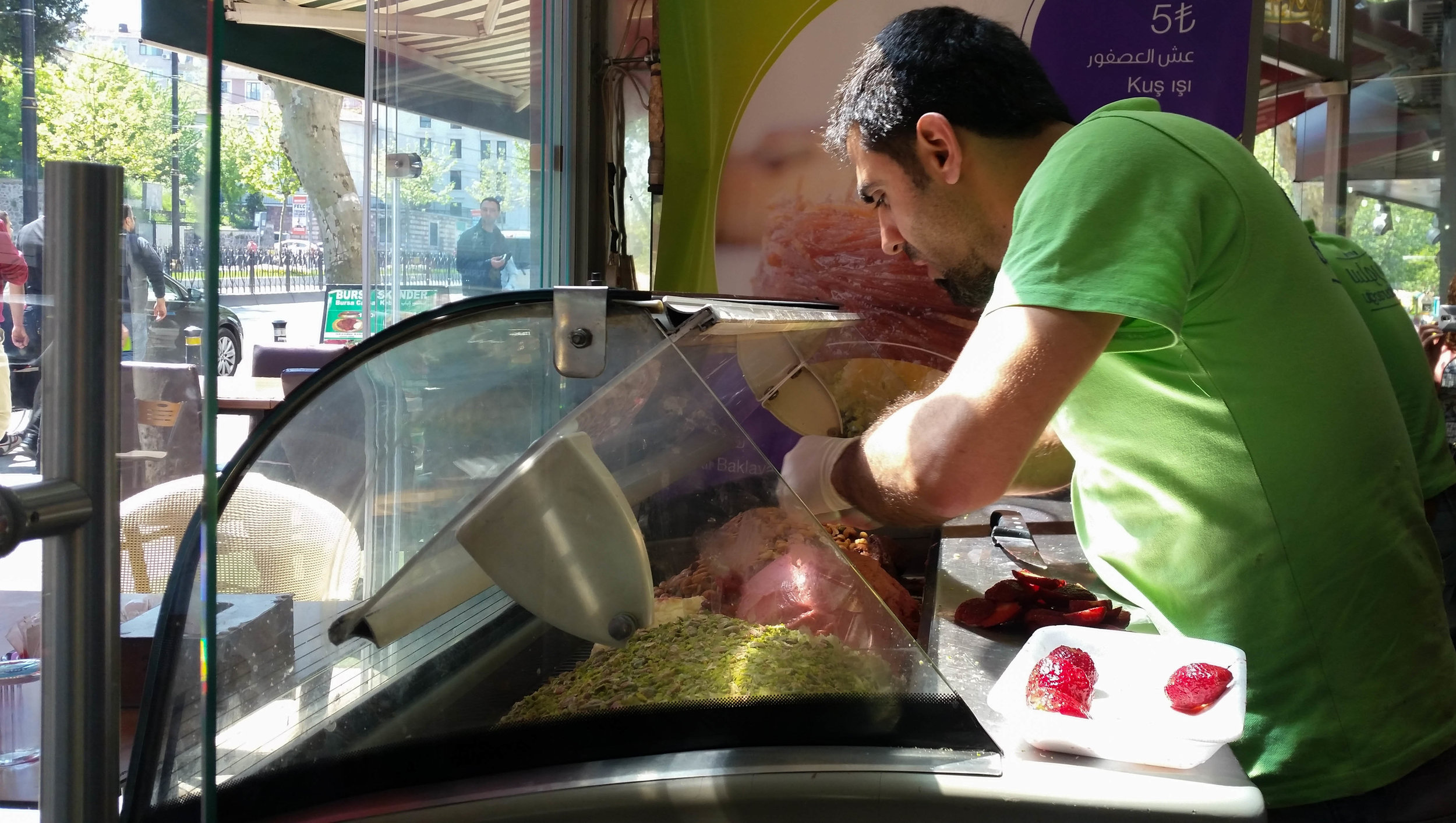 Rashed prepares ice cream by decorating freshly made mounds of it with fresh fruit and crushed pistachio. (Photo by Dalia Mortada)