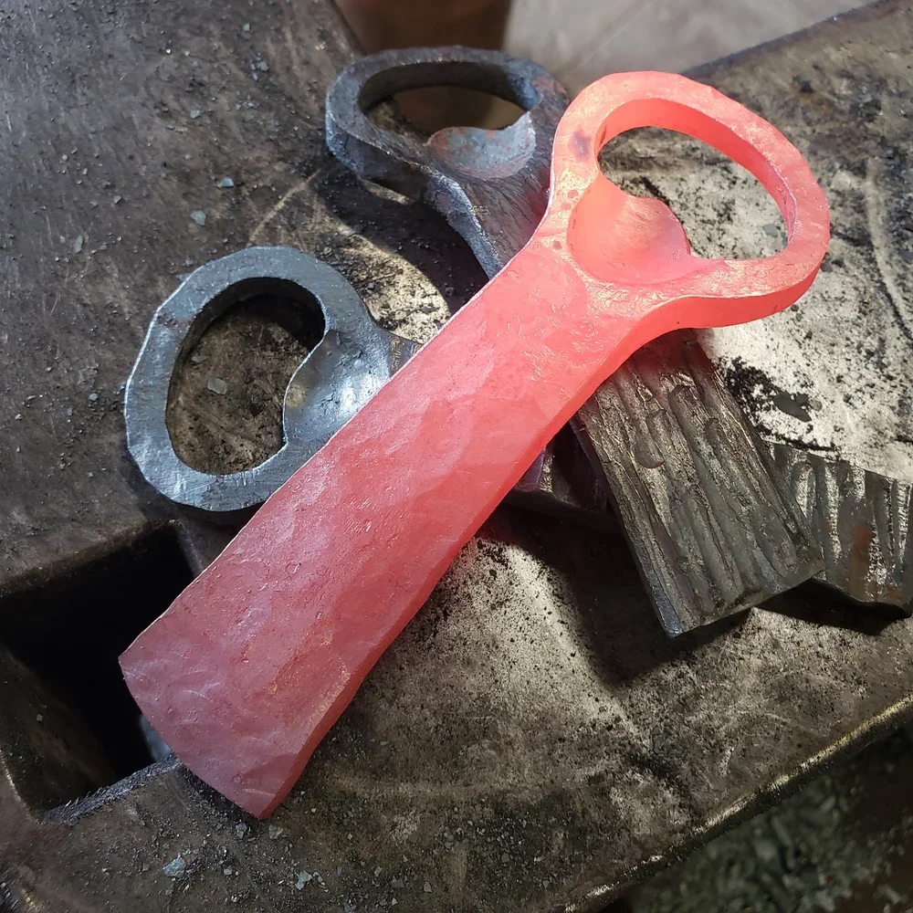 A red spanner or wrench placed on a metal workbench with two black metal washers nearby.