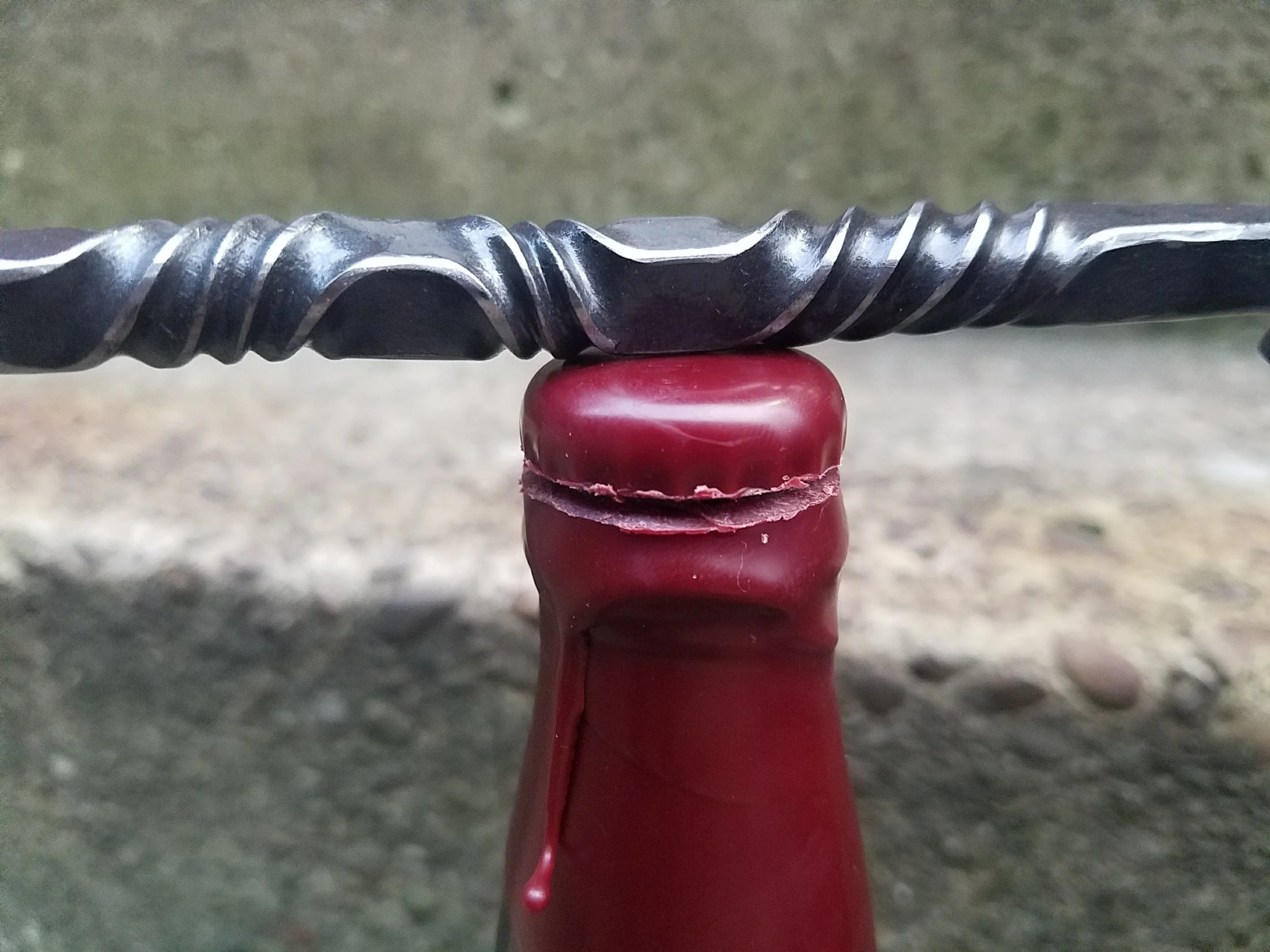 Hand forged, hand ground bottle opener complete with serrated edge for opening wax dipped bottles. Shown here resting atop a freshly cut wax dipped bottle.