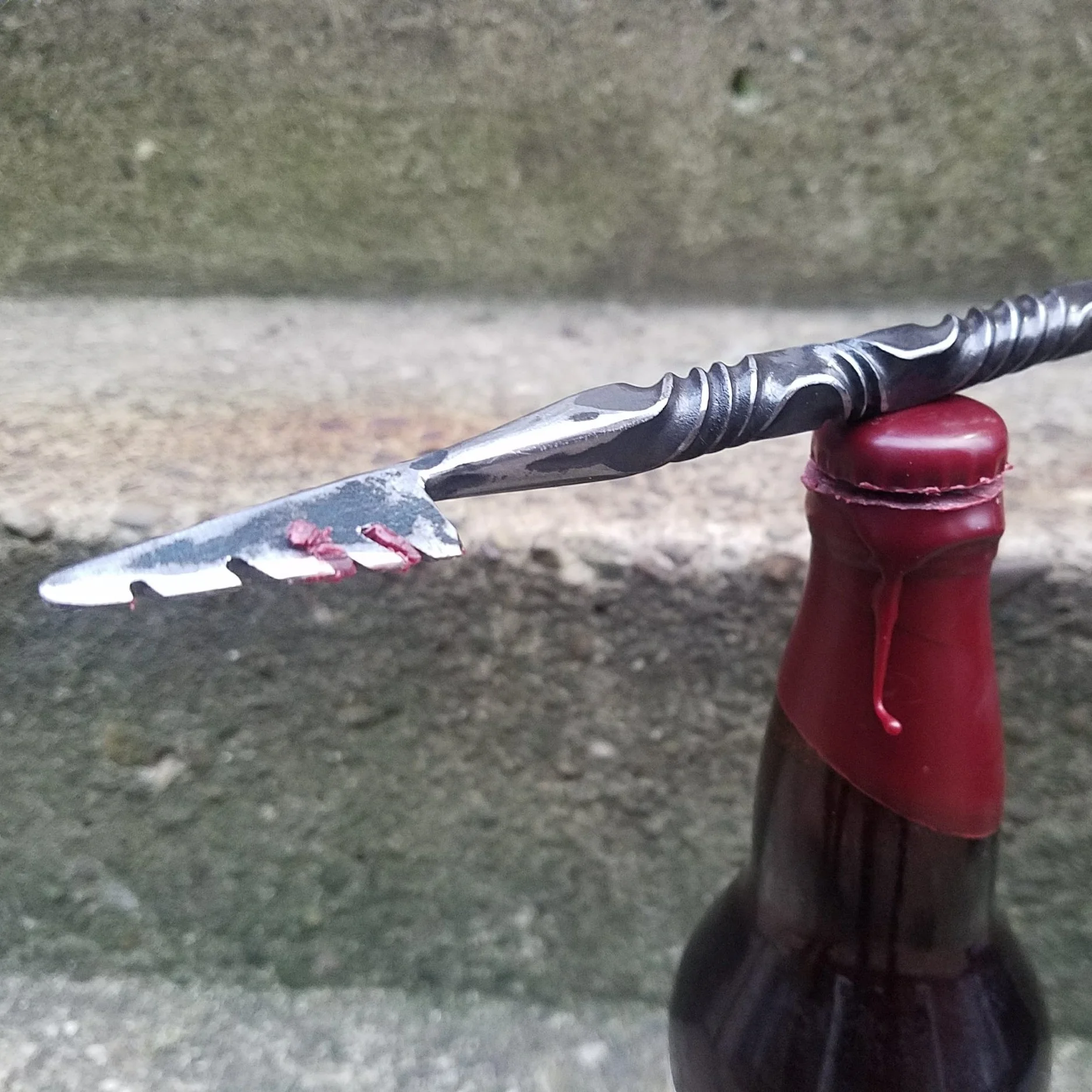 Hand forged, hand ground bottle opener complete with serrated edge for opening wax dipped bottles. Shown here resting on a freshly cut wax dipped beer bottle.