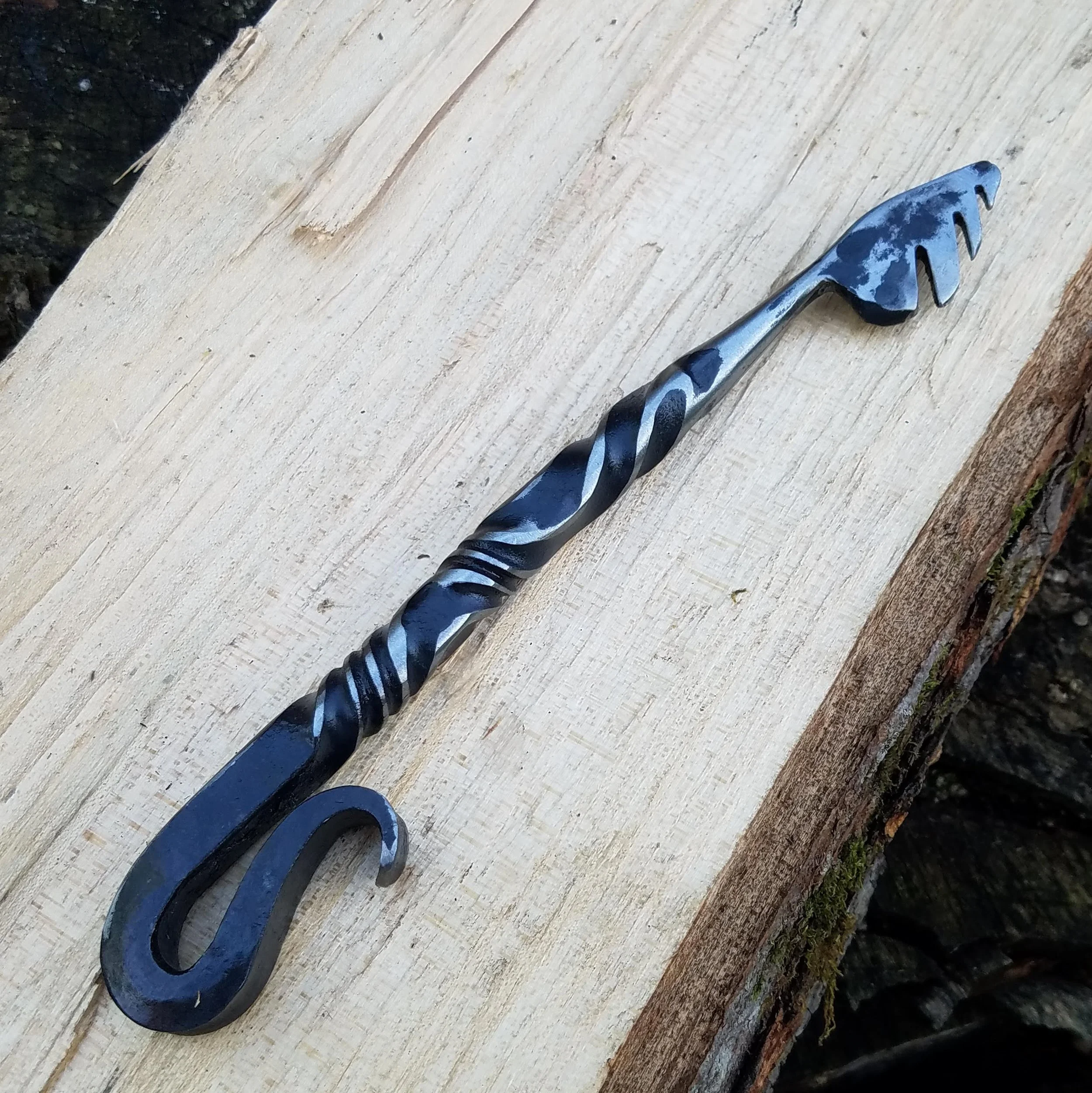 Hand forged, hand ground bottle opener complete with serrated edge for opening wax dipped bottles. Shown here resting on wood.