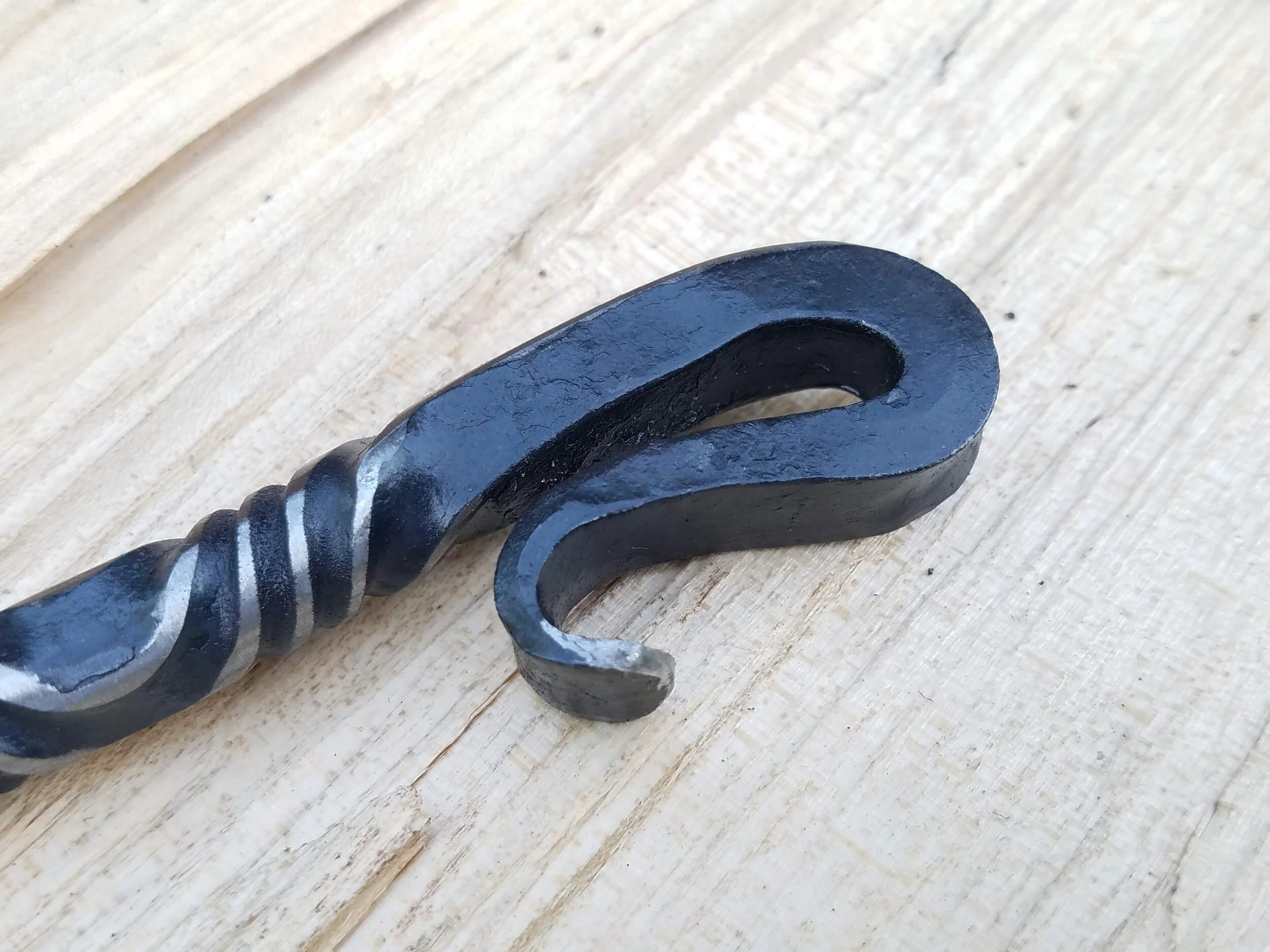Close of up the bottle opening end of this hand forged, hand ground bottle opener complete with serrated edge for opening wax dipped bottles.
