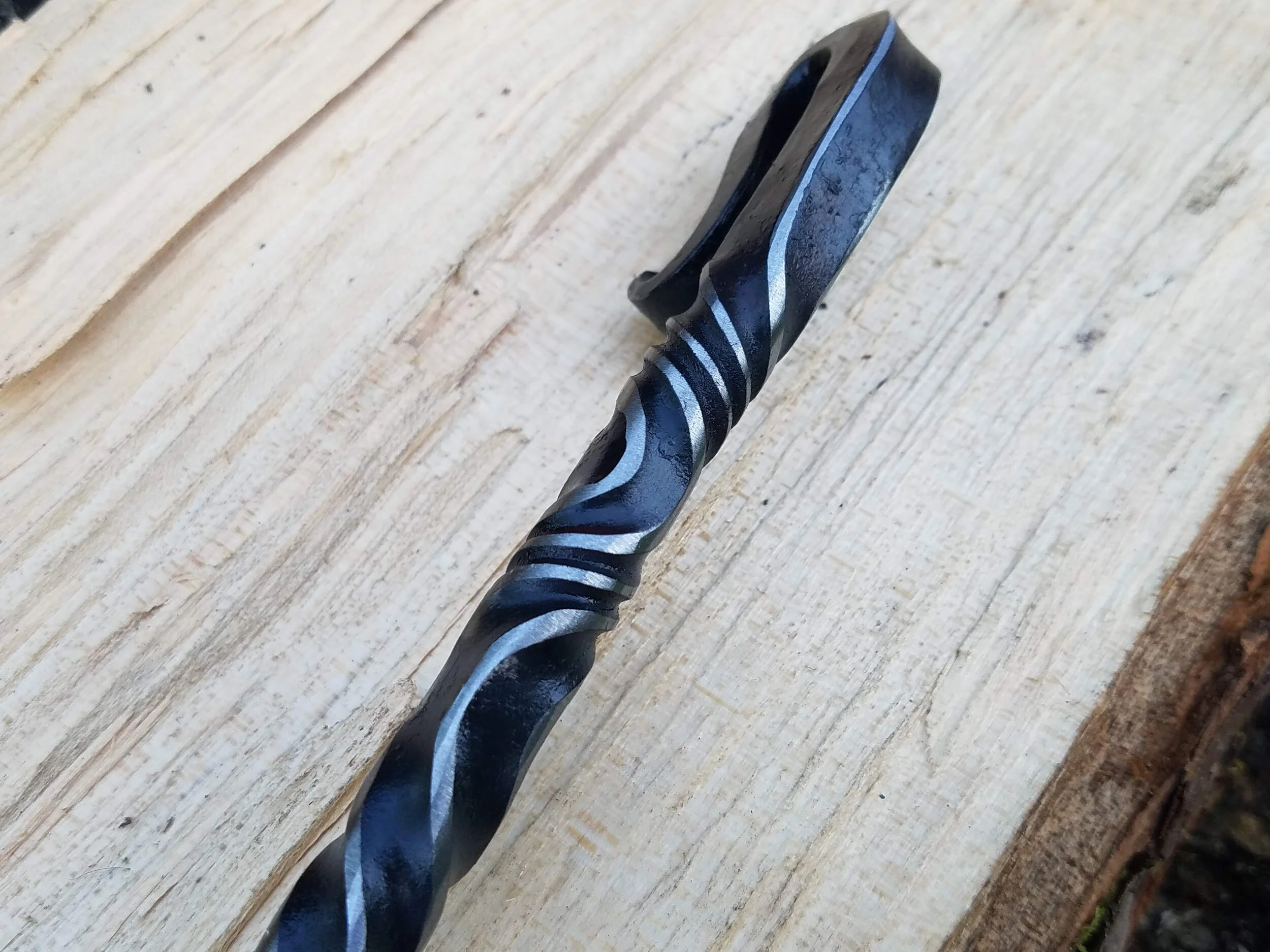 Hand forged, hand ground bottle opener complete with serrated edge for opening wax dipped bottles. Shown here resting on wood.