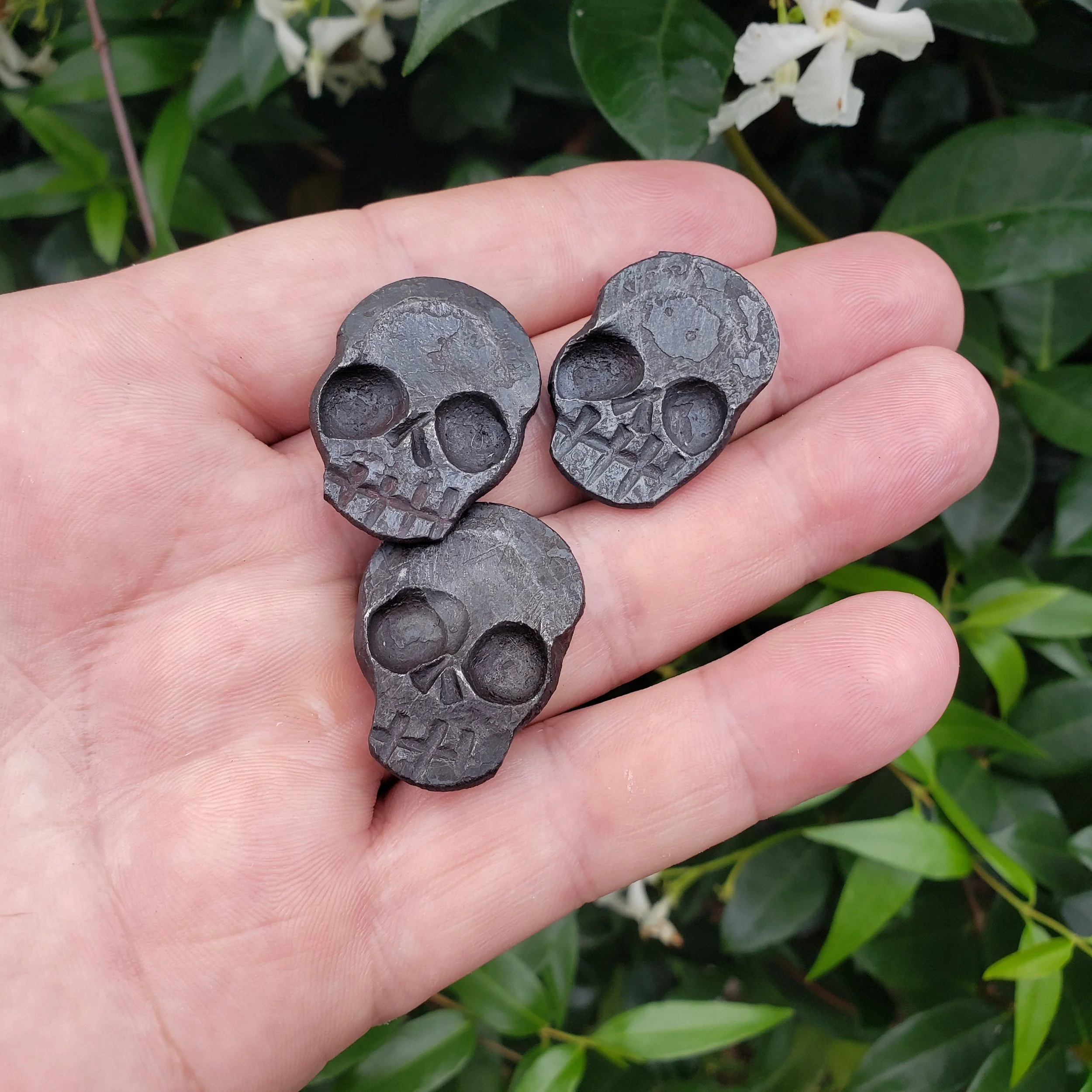 A "Memento Mori" worry coin, hand forged from 3/4" round stock steel and shaped in the form of a skull. Shown here ready held in the hand for scale.