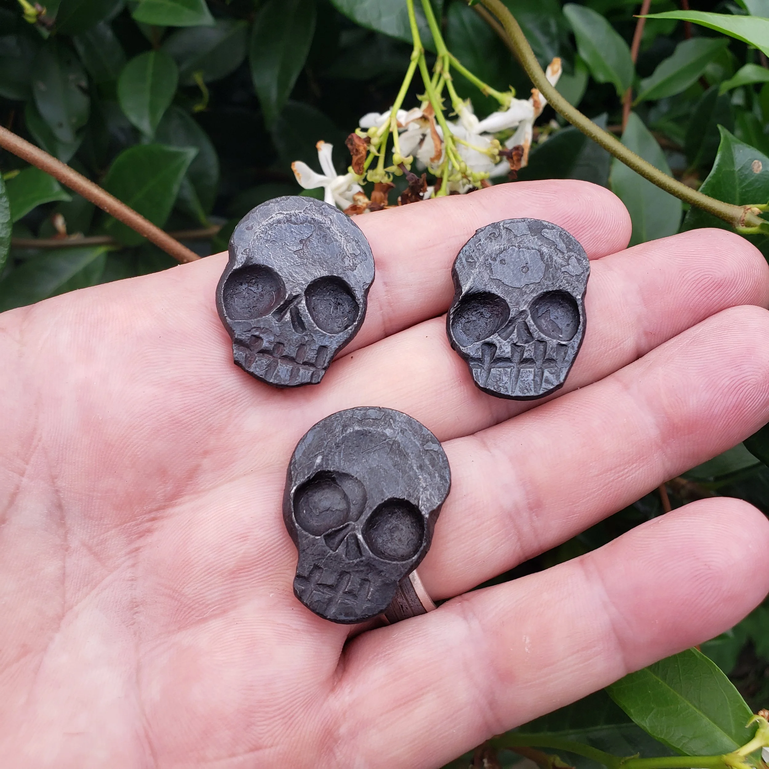 A "Memento Mori" worry coin, hand forged from 3/4" round stock steel and shaped in the form of a skull. Shown here ready held in the hand for scale.