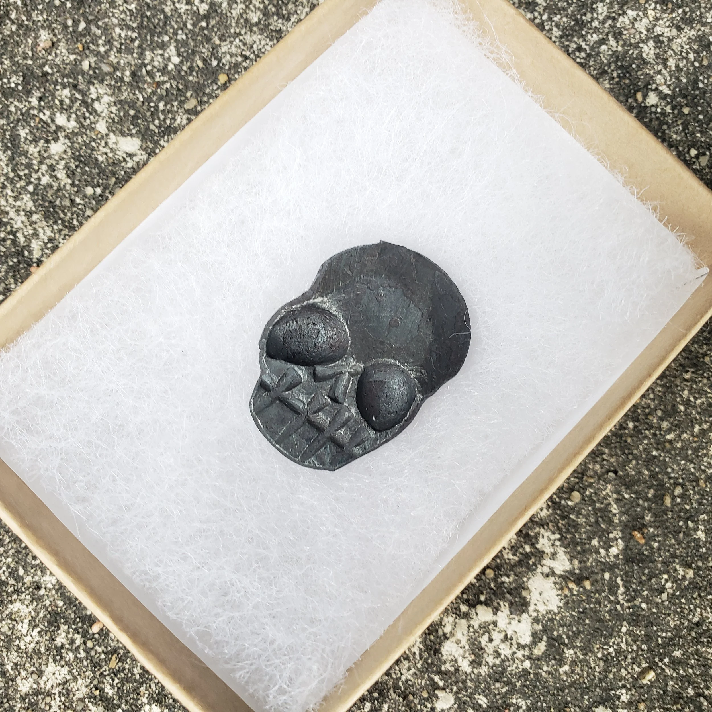 A "Memento Mori" worry coin, hand forged from 3/4" round stock steel and shaped in the form of a skull. Shown here ready to be packaged and shipped.