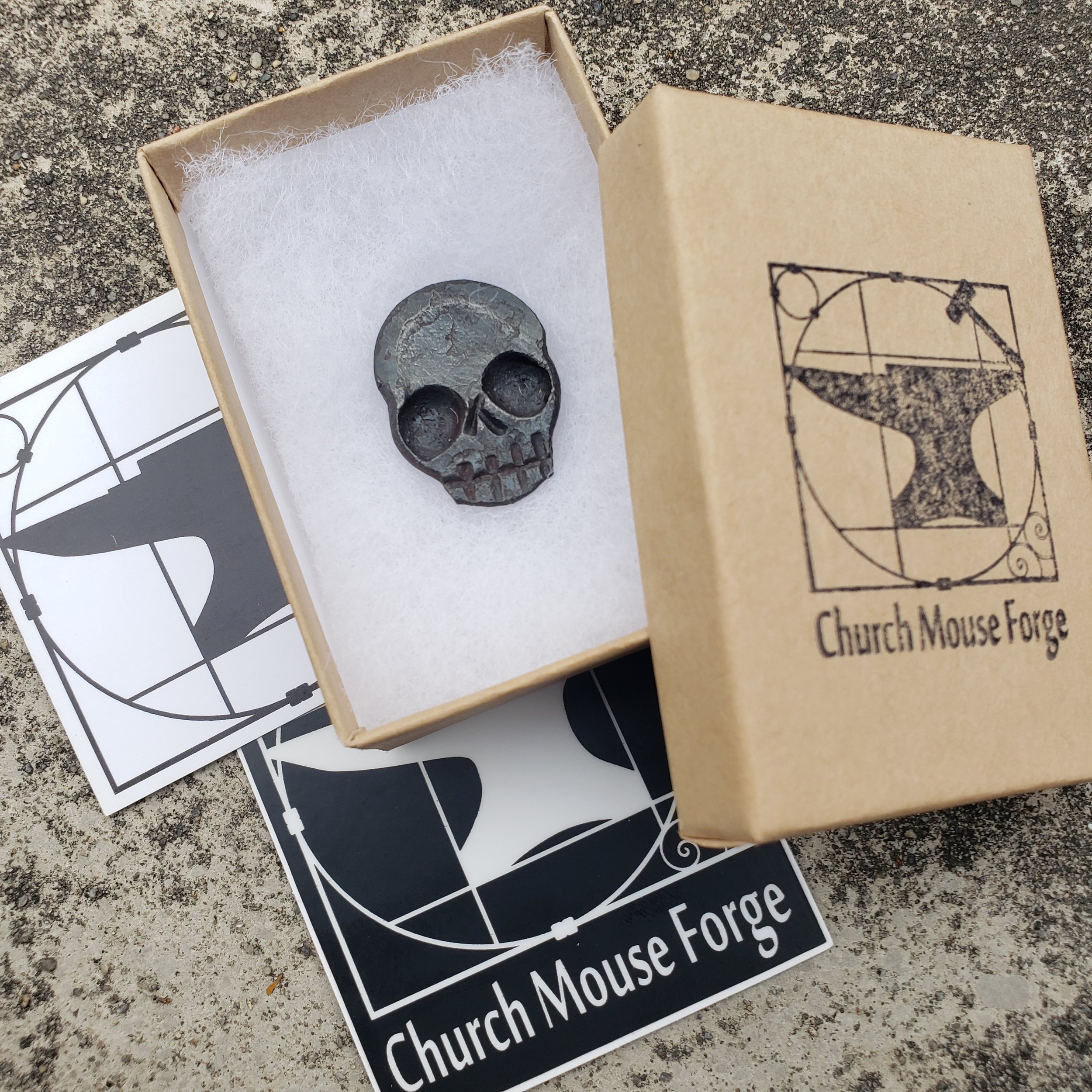 A "Memento Mori" worry coin, hand forged from 3/4" round stock steel and shaped in the form of a skull. Shown here ready to be packaged and shipped.