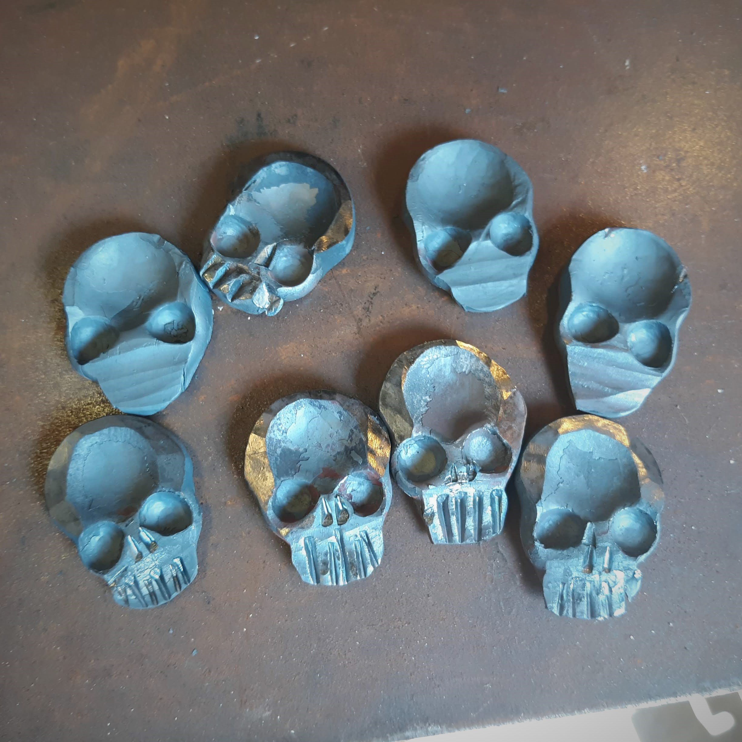 A "Memento Mori" worry coin, hand forged from 3/4" round stock steel and shaped in the form of a skull. Several steps in the process shown here as the coins are developed.