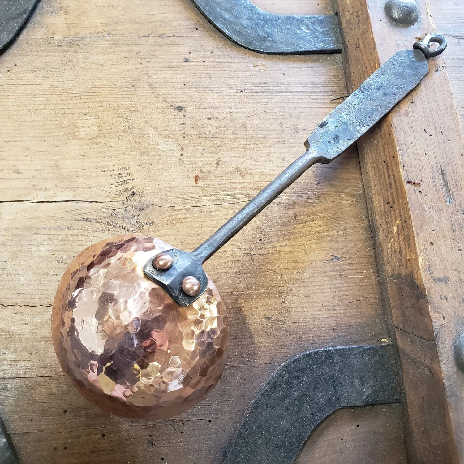Hammer with a hammered copper head lying on a wooden surface.