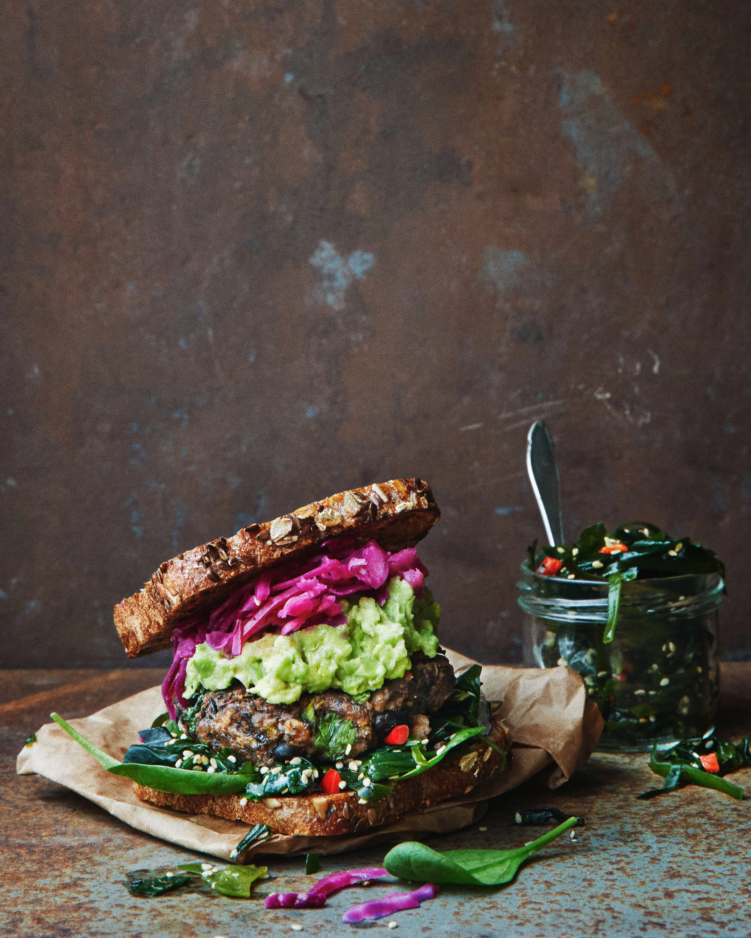 Black bean burger with seaweed salad, mashed avocado and pickled red cabbage