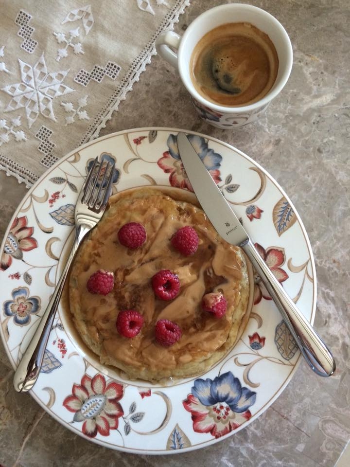 homemade banana pancakes with peanut butter and raspberries. coffee by lavazza.