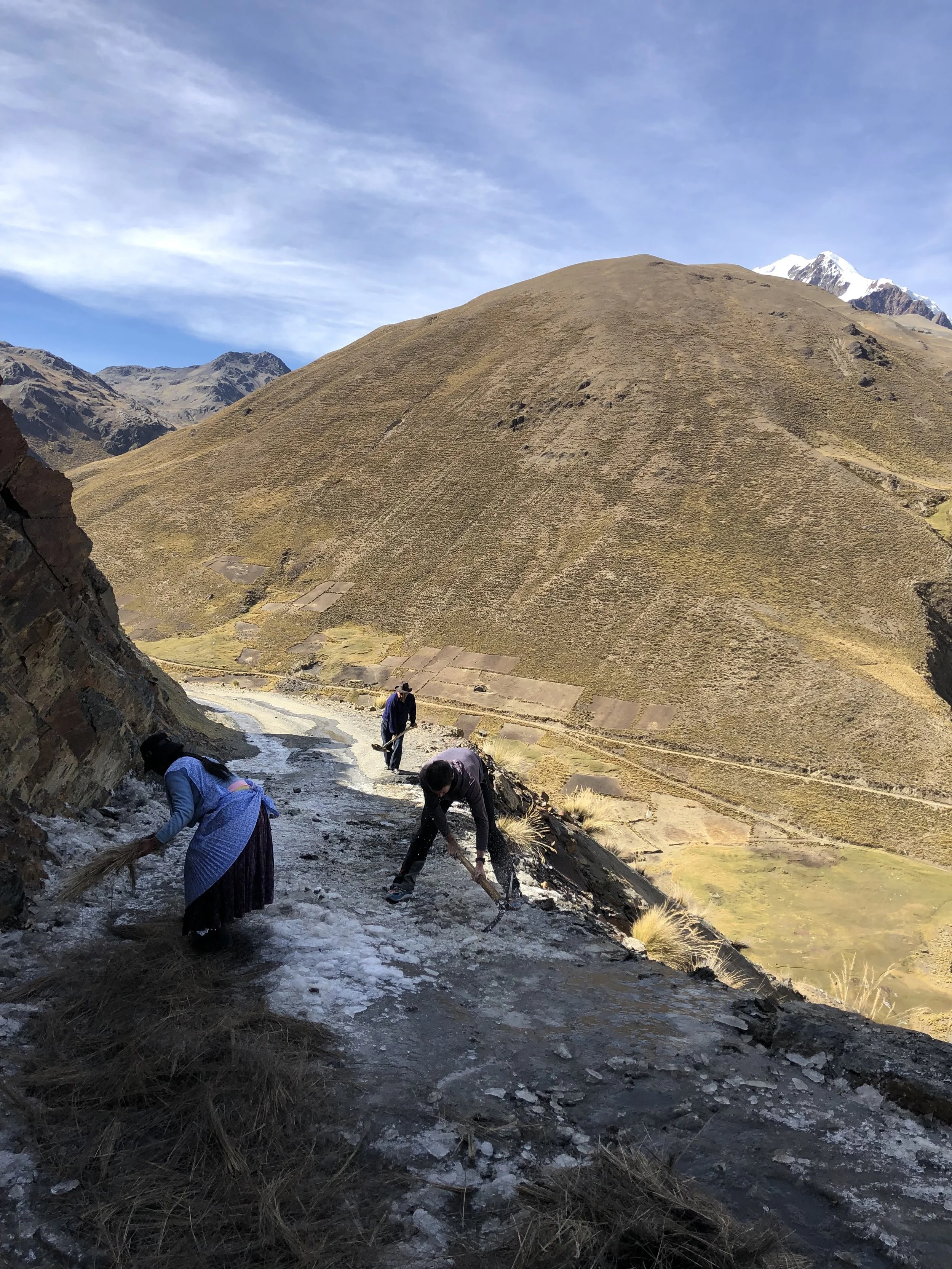 Dale grabs a pickaxe and helps clear ice from the road as Illimani looms.