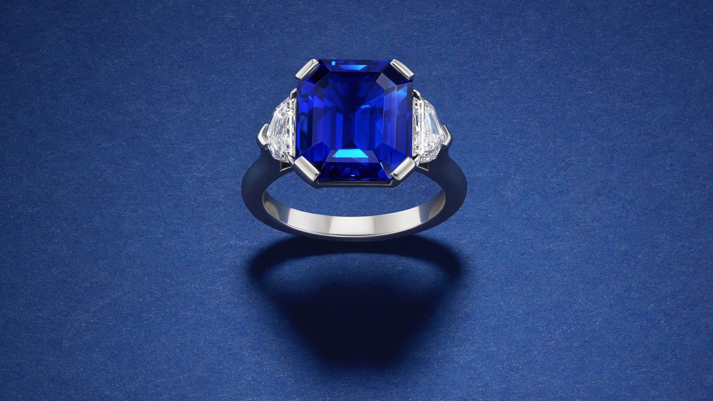 large emerald cut sapphire ring set in platinum with epaulette side diamonds