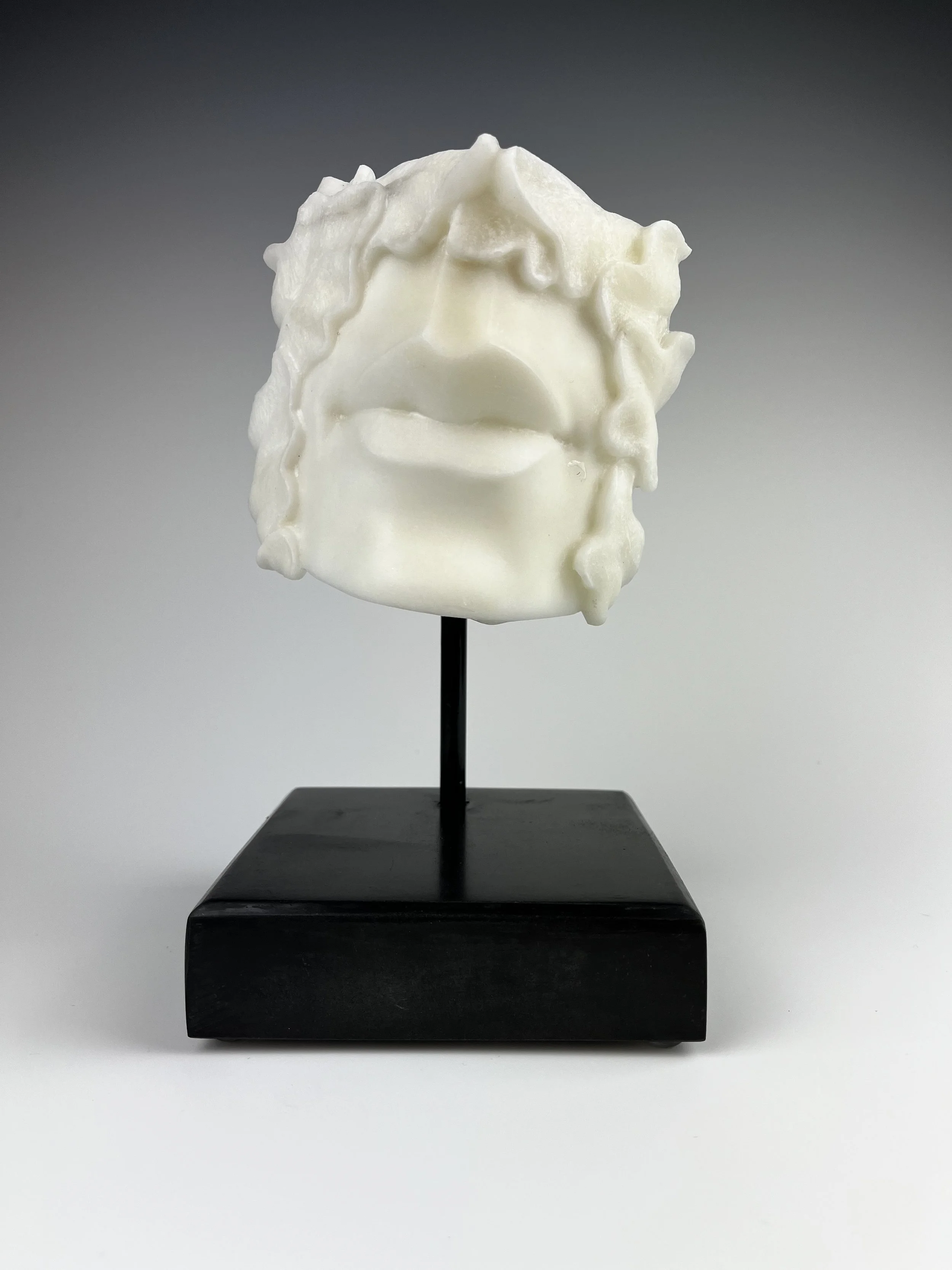 Peace is a white marble sculpture with a mouth surrounded by carved leaves on a steel post and stone base.