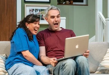 An image of two characters laughing at content appearing on their laptop.