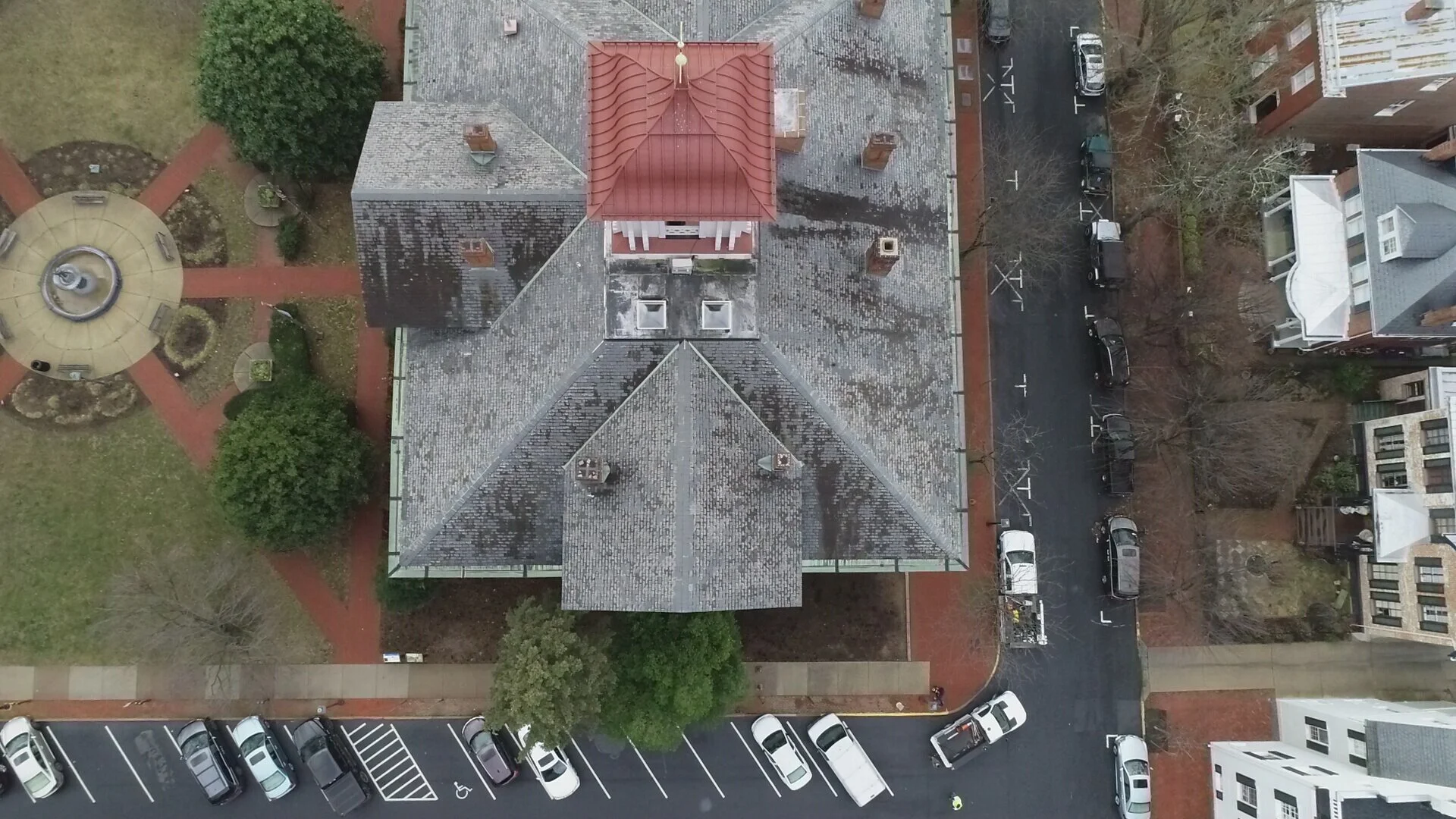 drone image of gray City Hall Roof (11) with parking spaces and cars around it.