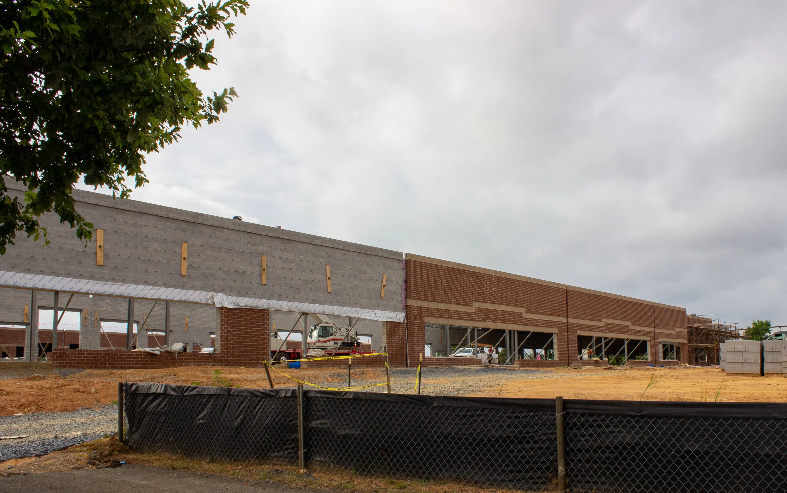 A large building under construction, surrounded by scaffolding, against a backdrop of cloudy skies..jpg