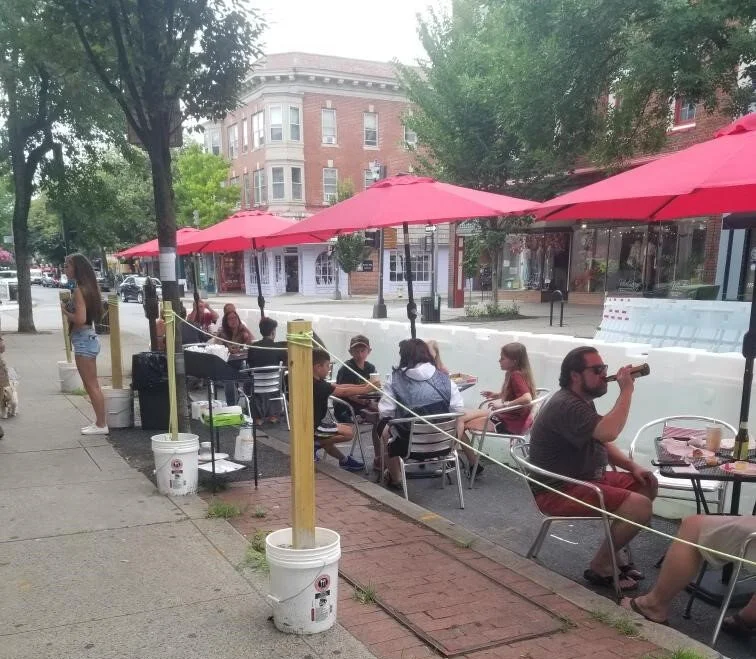 An outdoor seating area filled with people under red tents.