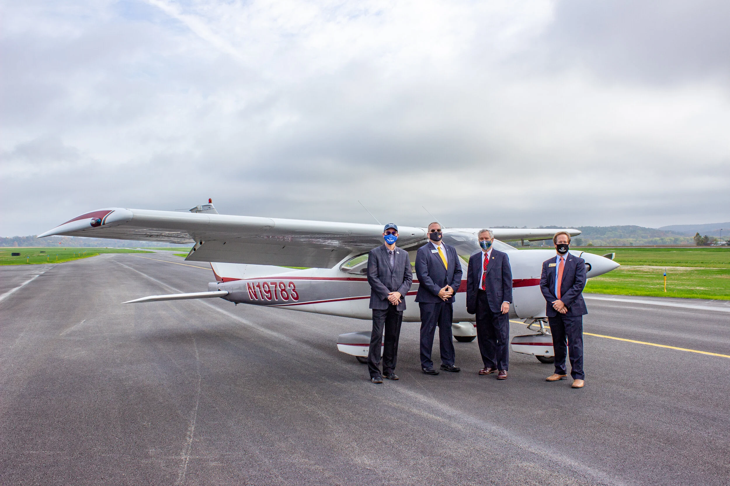 four people standing in front of plane on tarmac.jpg