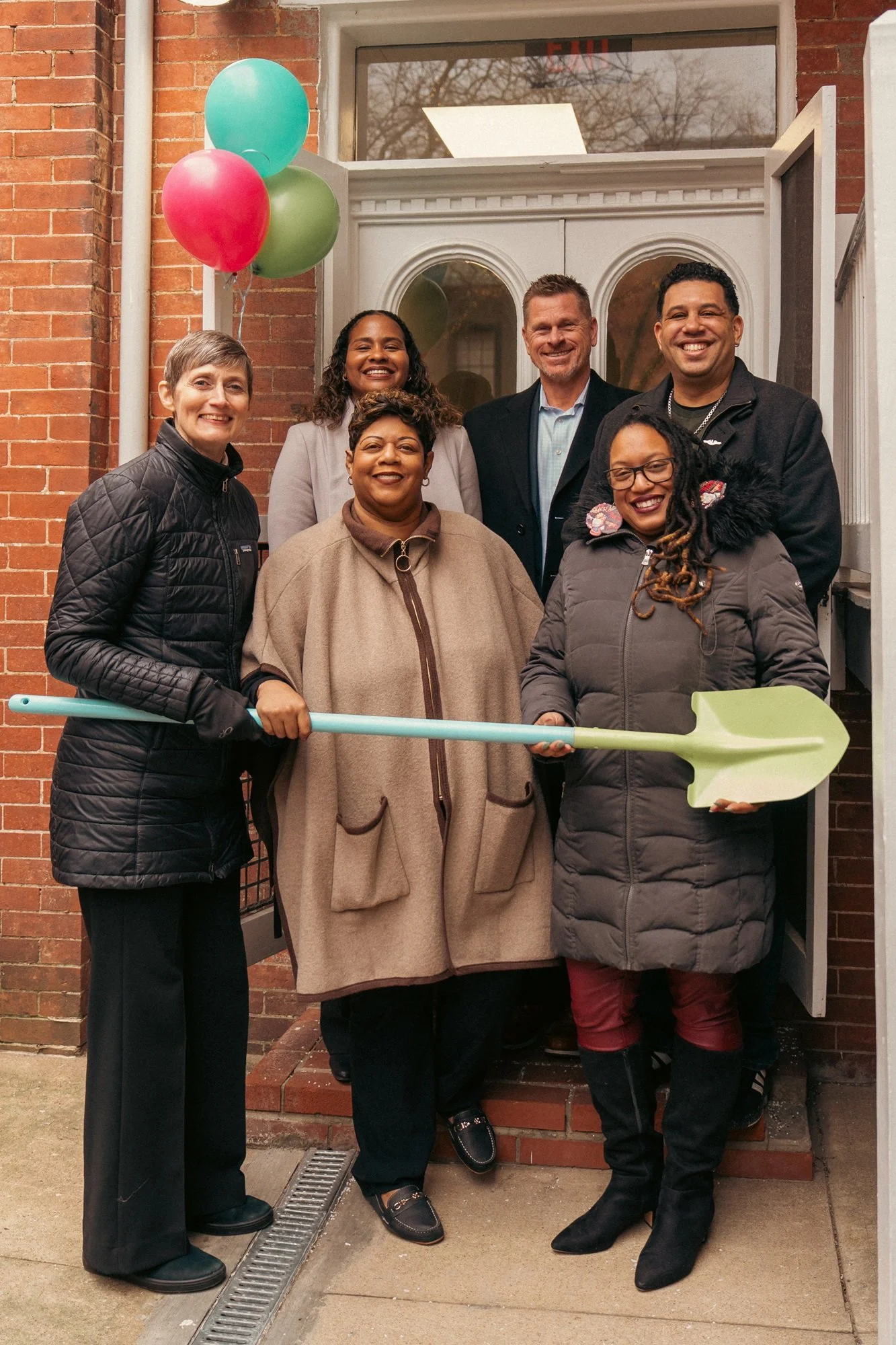  Group photo with groundbreaking shovel in front of building. 