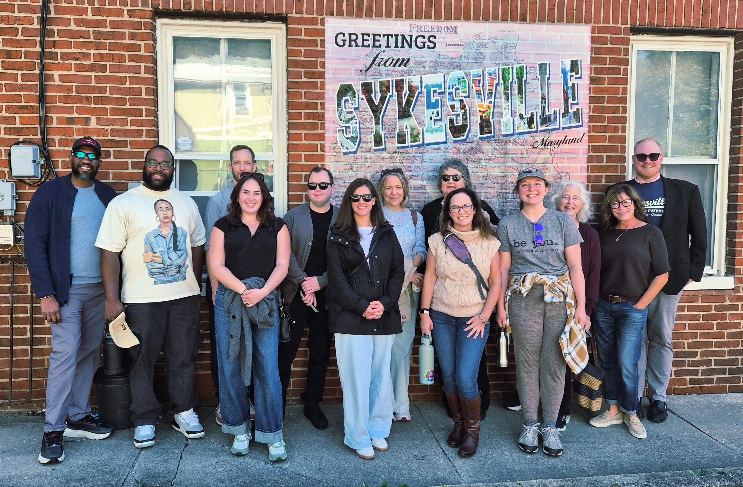 group of people standing in front of brick wall.