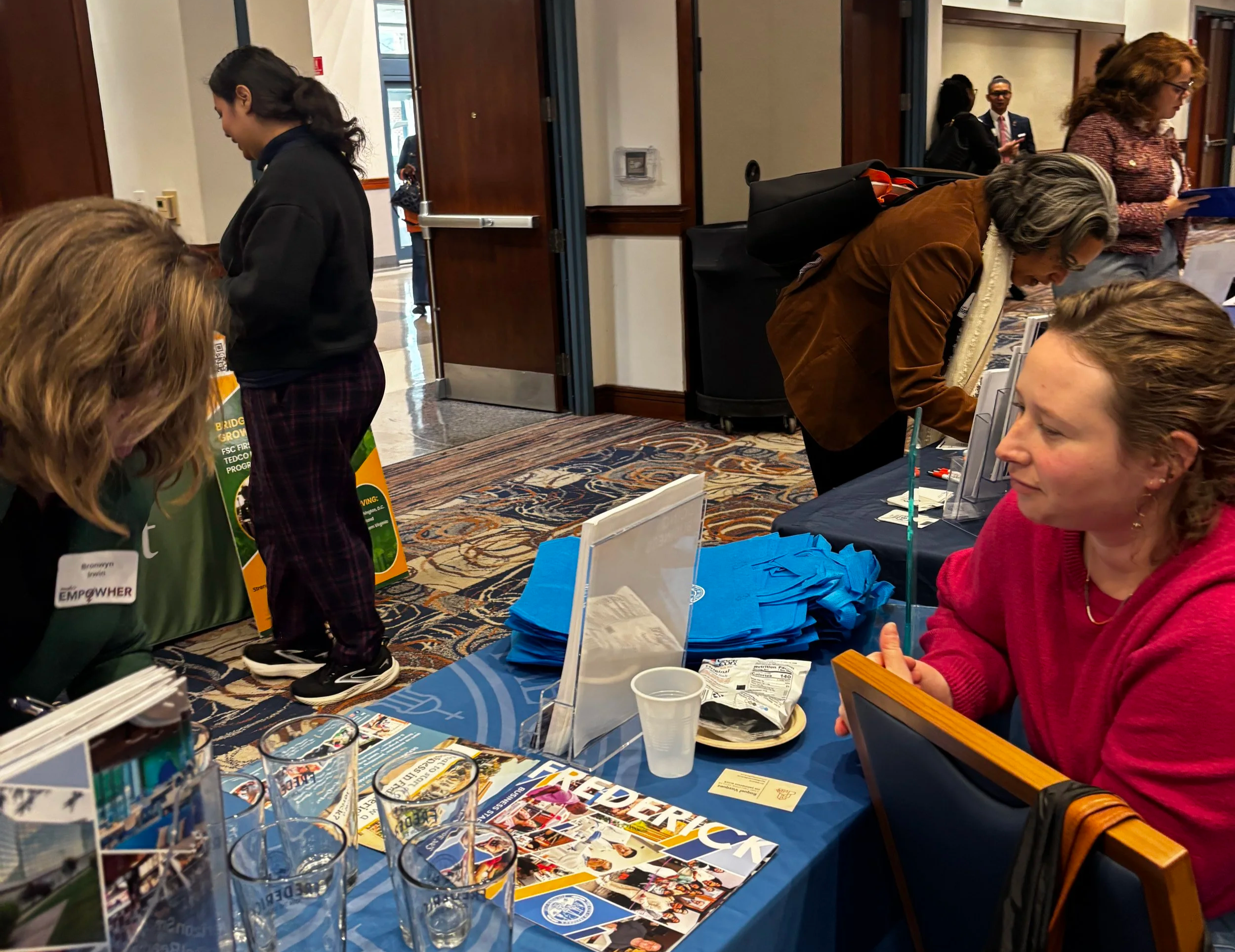 two people interfacing at table with people in background