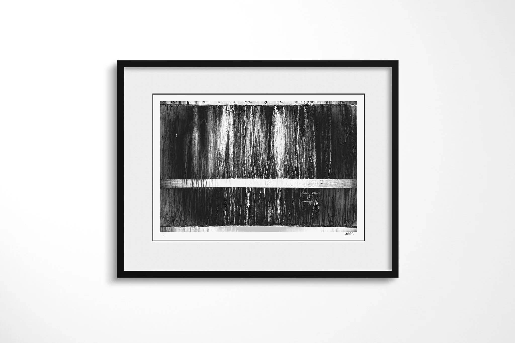 Derelict presented in a black frame and wide white mount, showing a dark rectangular panel with vertical stains, hard edge lines and a pale horizontal reflective strip.