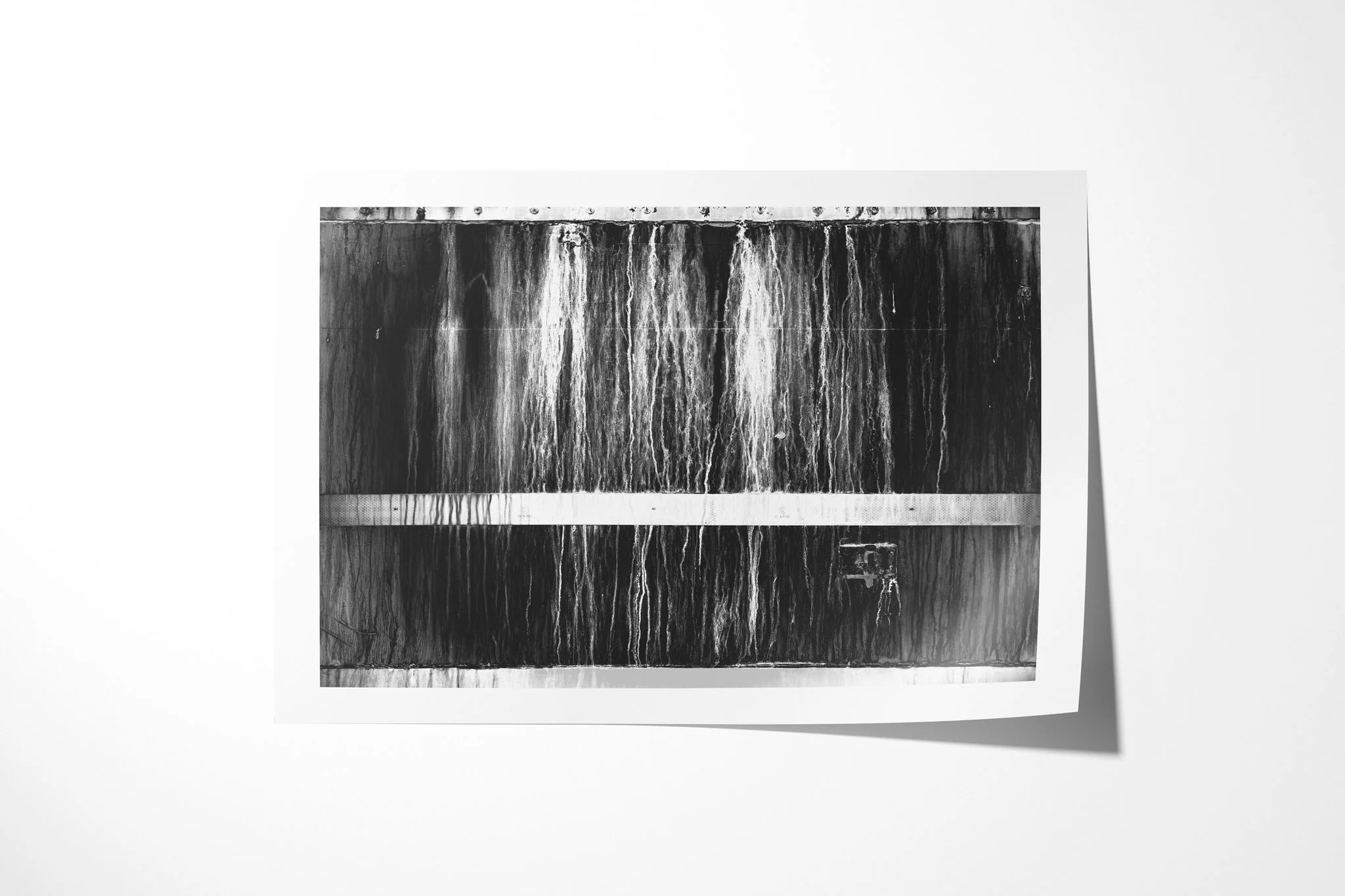 Derelict presented as an unframed fine art paper print, showing a dark rectangular panel with vertical stains, hard edge lines and a pale horizontal reflective strip.