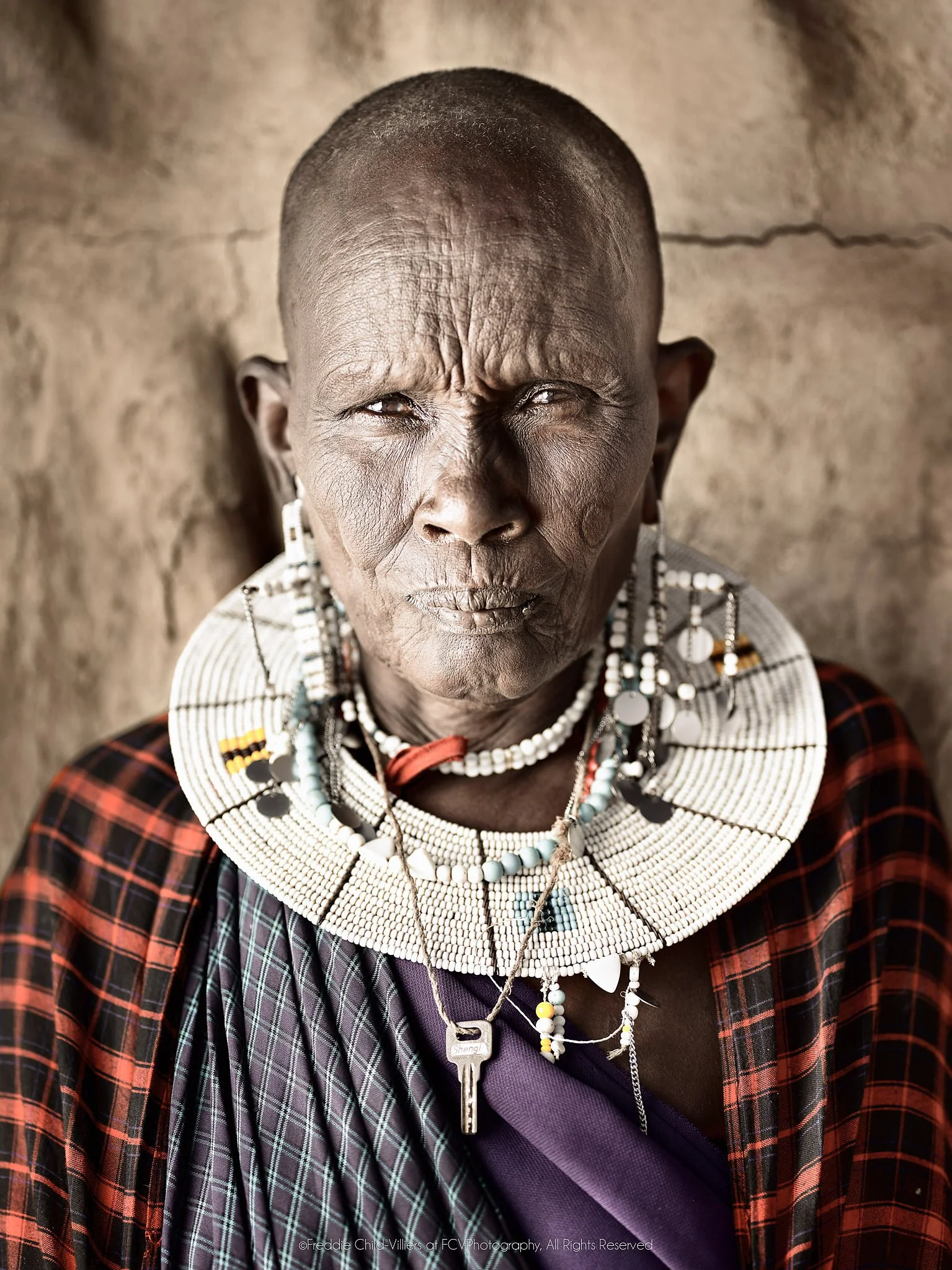 Naleku, a close portrait of a Maasai elder wearing a white bead collar and checked cloth.