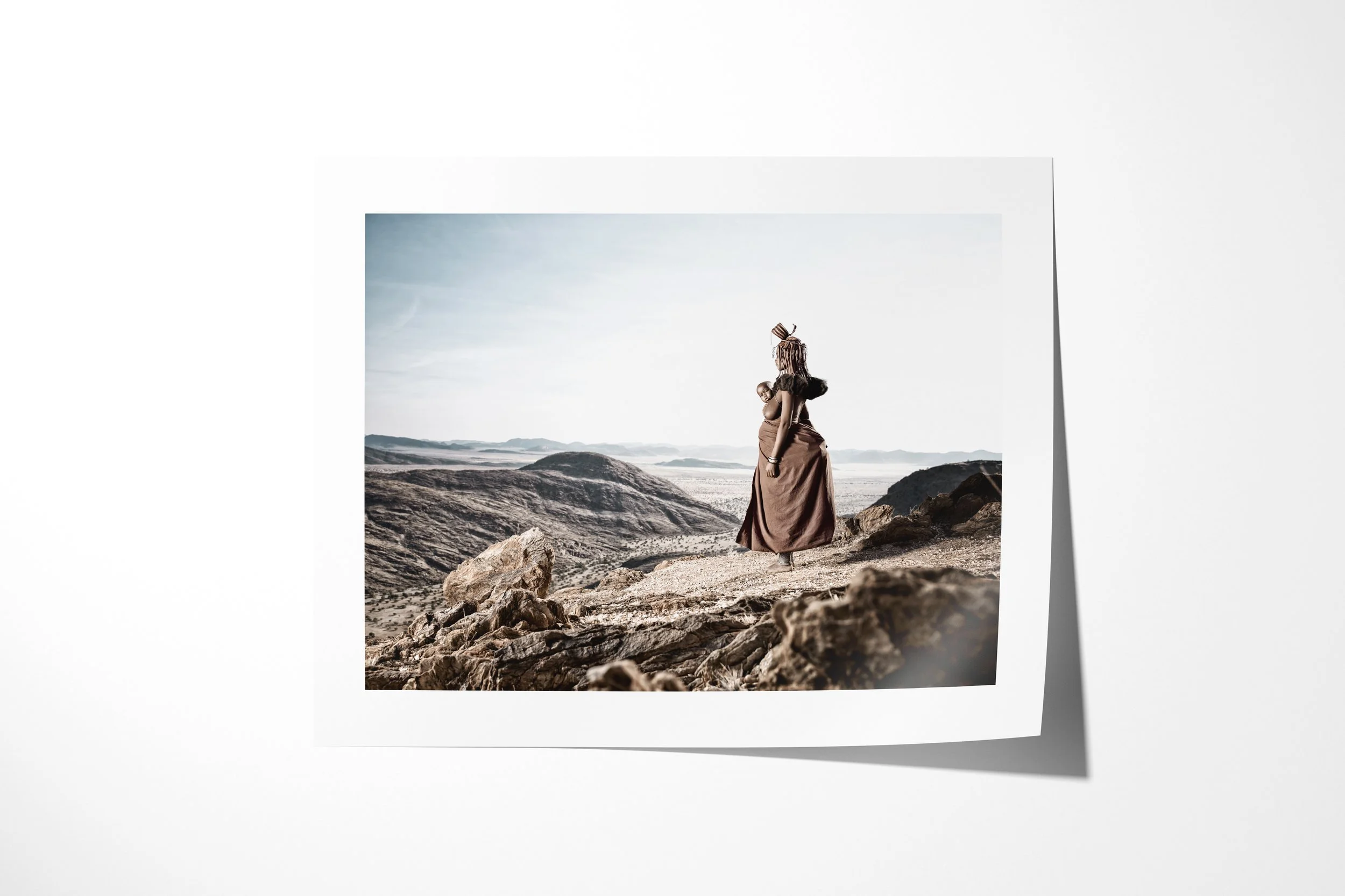 Fine art paper print of Venongore, showing Venongore carrying her child on her back while looking across the rocky Marienfluss.