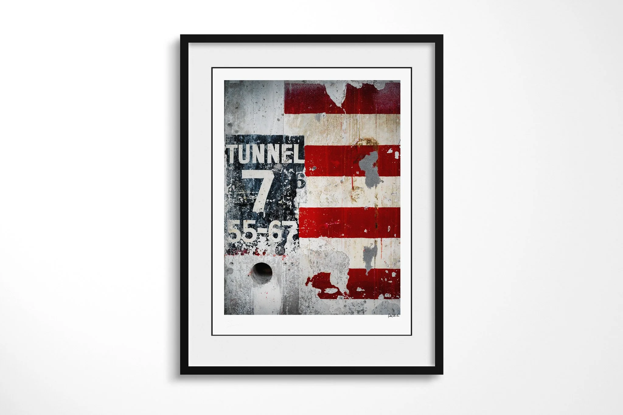 Black-framed fine art print of Weathered with a white mount, showing a distressed Tunnel 7 sign beside peeling red-and-white stripes and a circular recess on a weathered industrial wall.