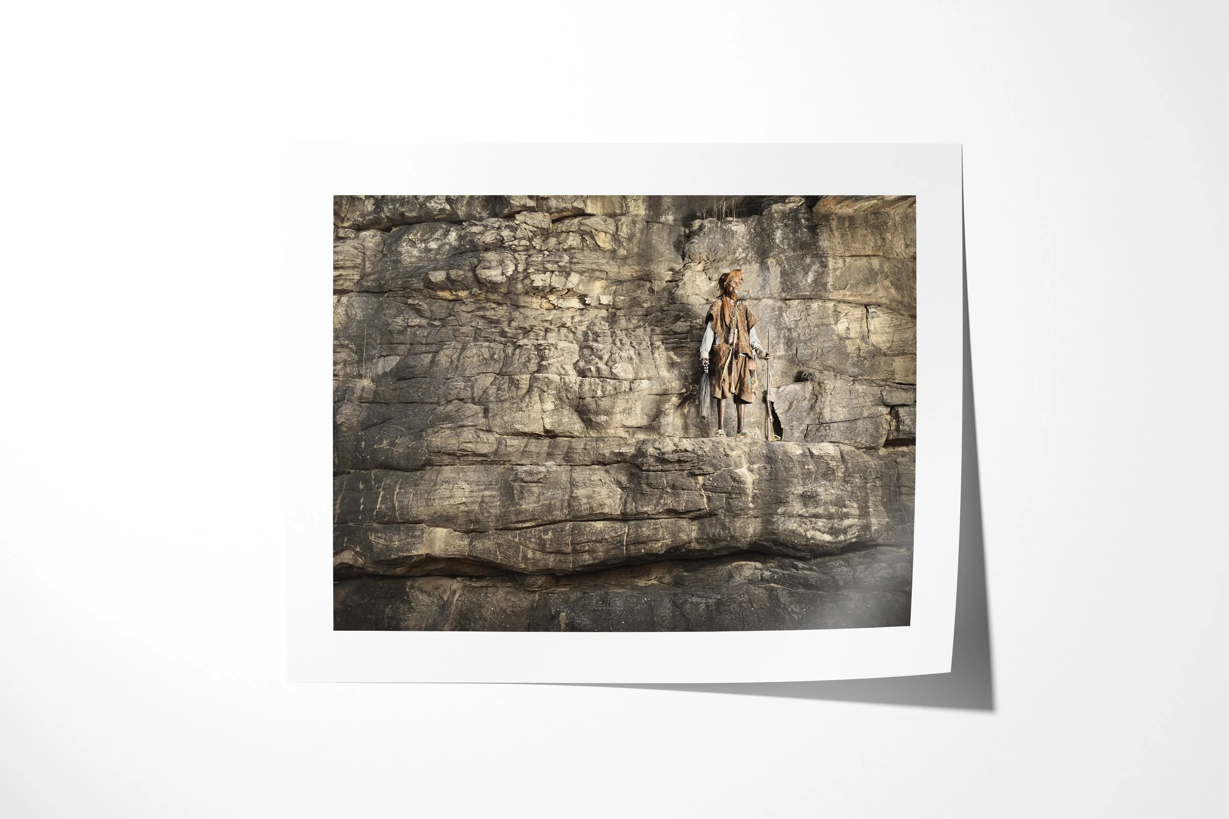 Fine art paper print of Anbaga, showing Anbaga standing alone against a vast banded sandstone cliff.