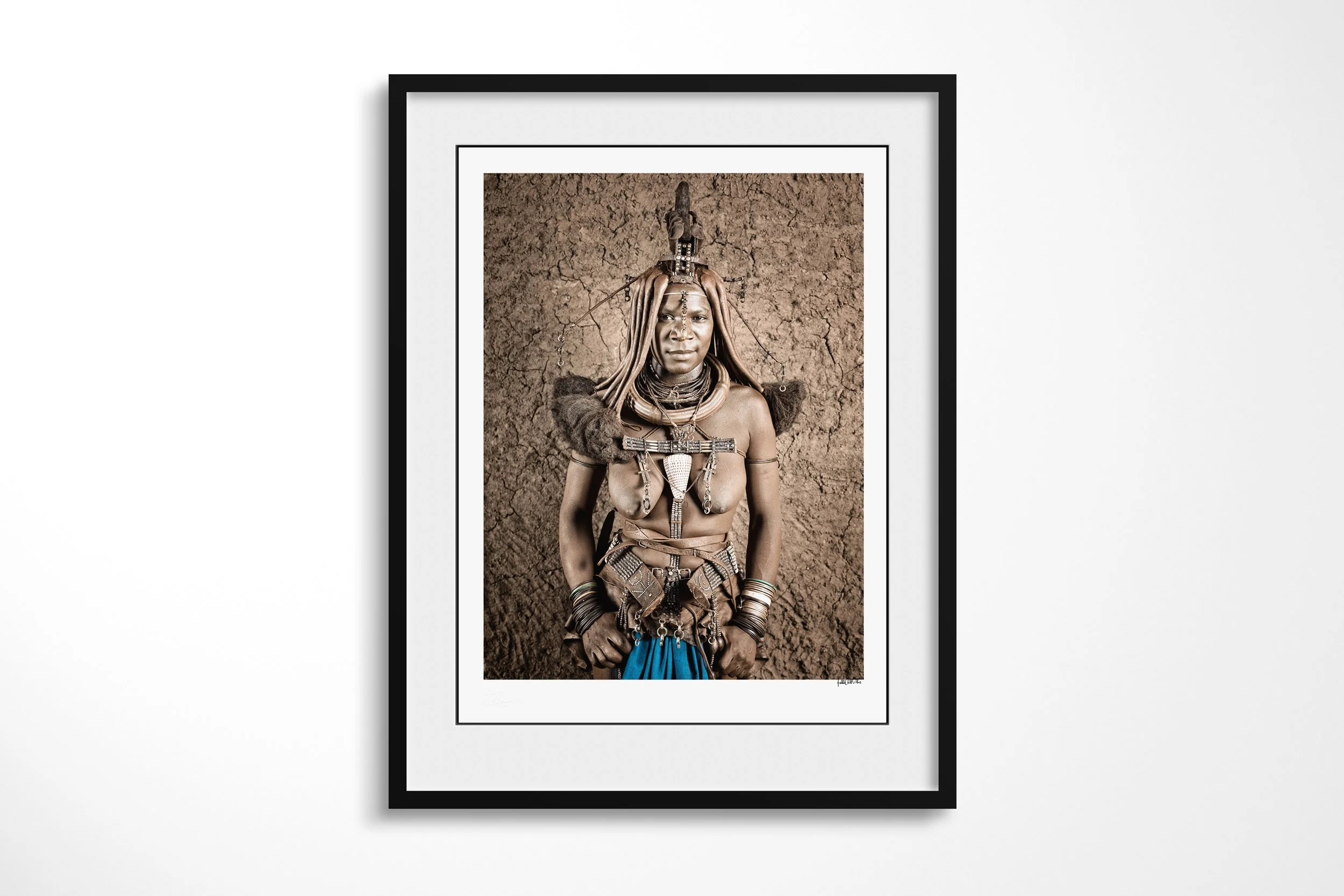 Framed presentation of Twahenwa II in a black frame and white mount, showing a close portrait of Twahenwa wearing an erembe headdress, otjize-dressed hair and layered jewellery.
