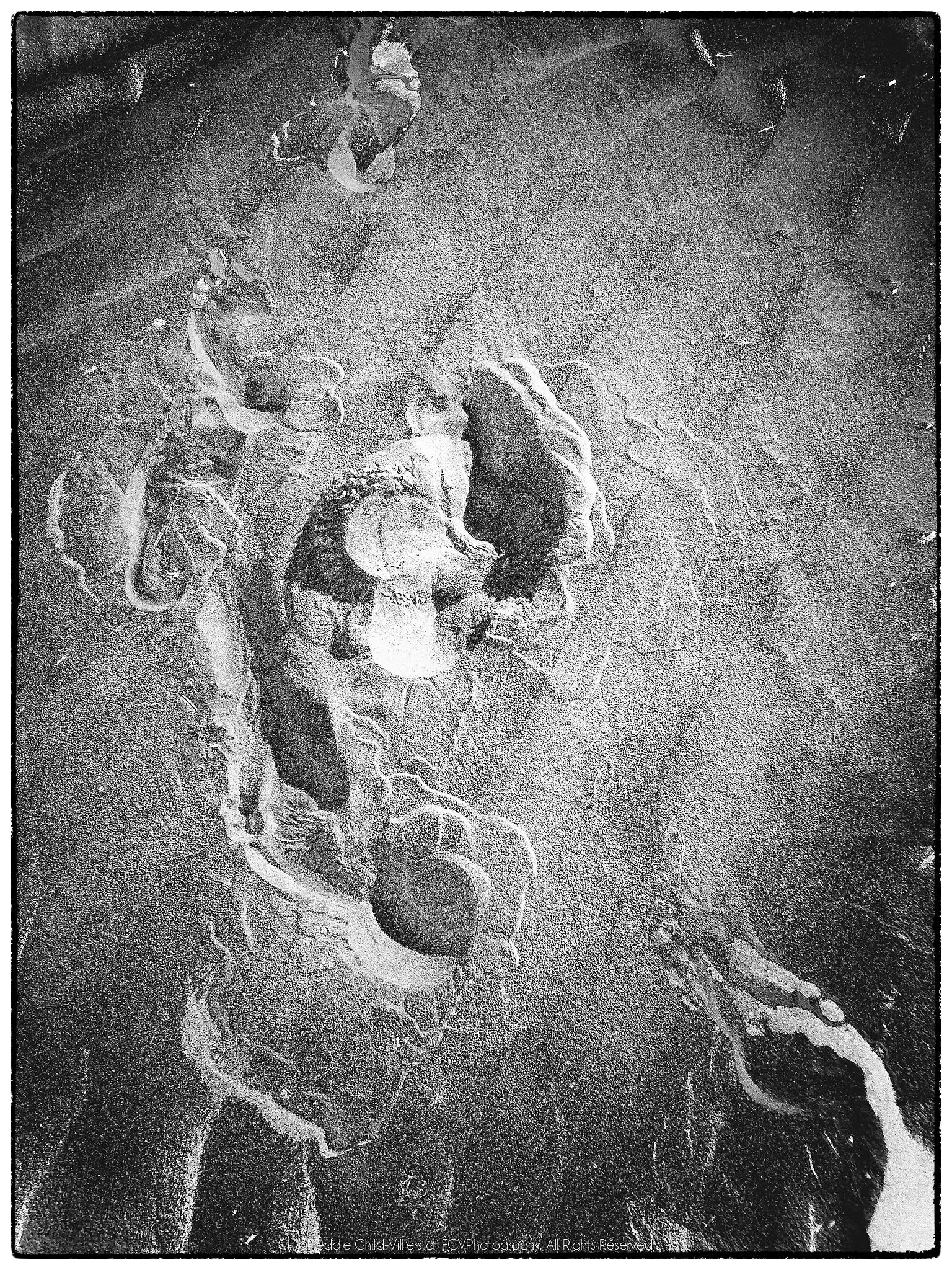 Overlapping shoe impressions and scuffed marks pressed into a dark granular surface.