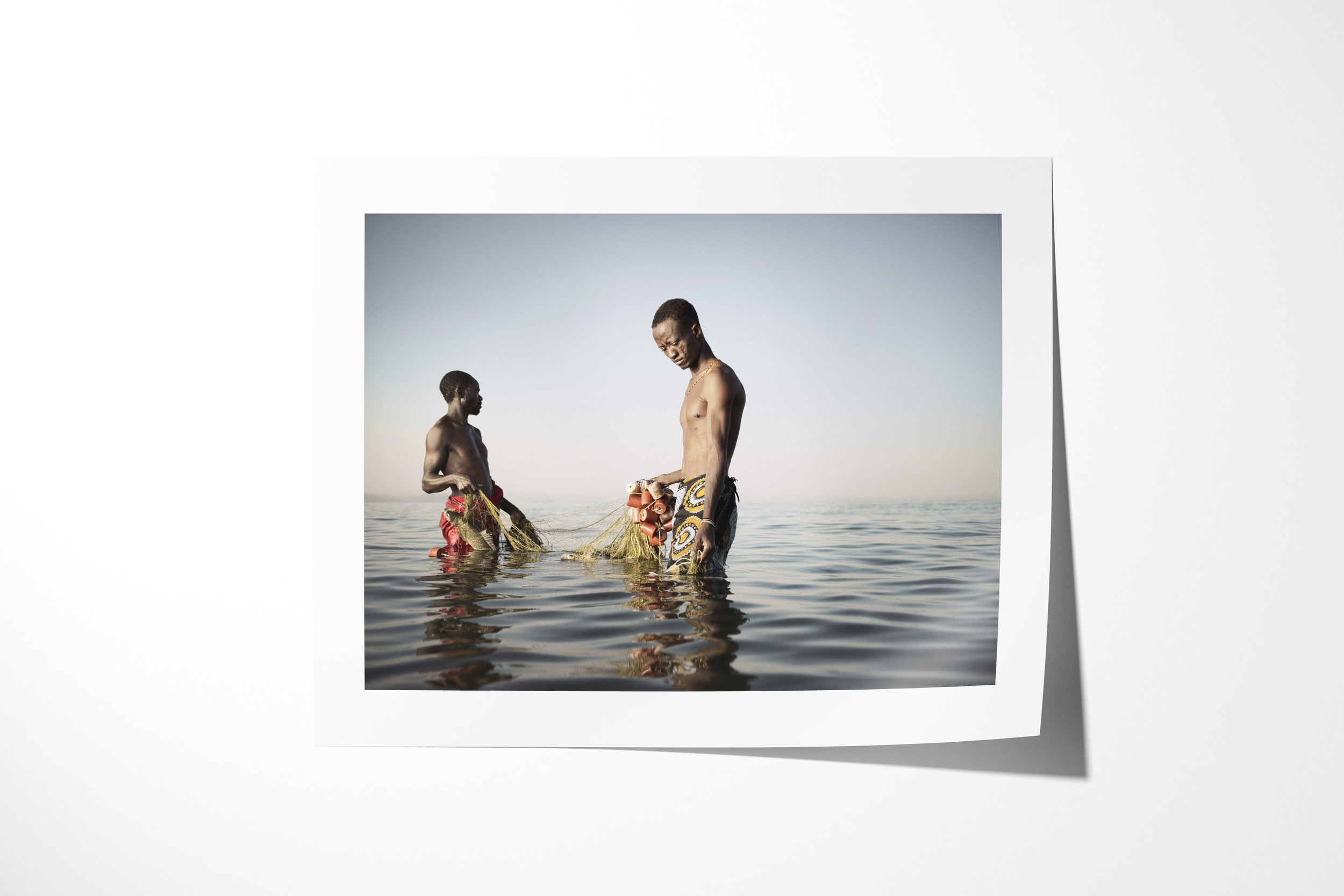 Fine art paper print of Jeremy & Zacheus, showing two El Molo fishermen wading in Lake Turkana as they retrieve a net.