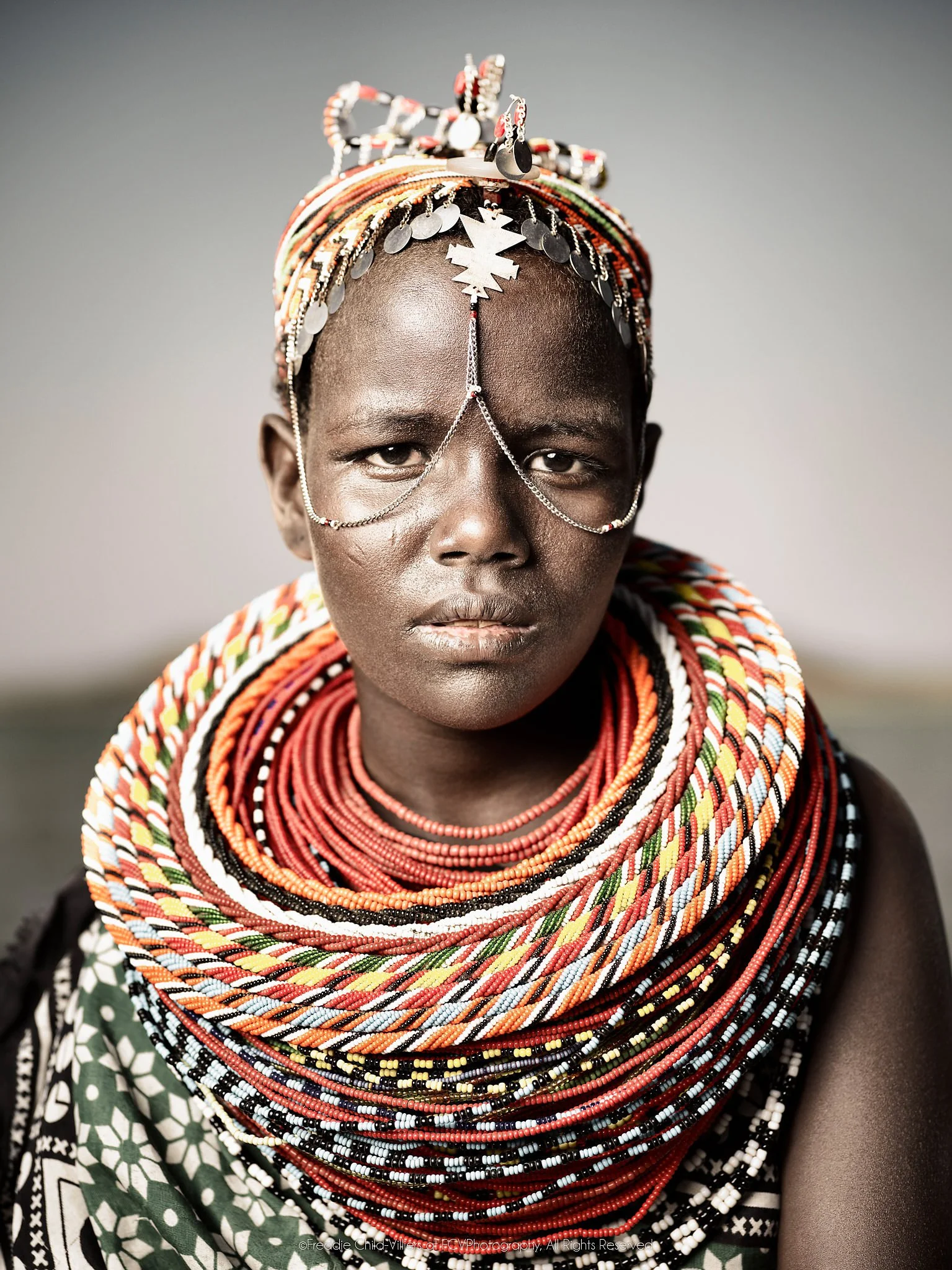 Nadirie, a close portrait of an El Molo woman wearing layered beadwork and fine chains across her face.