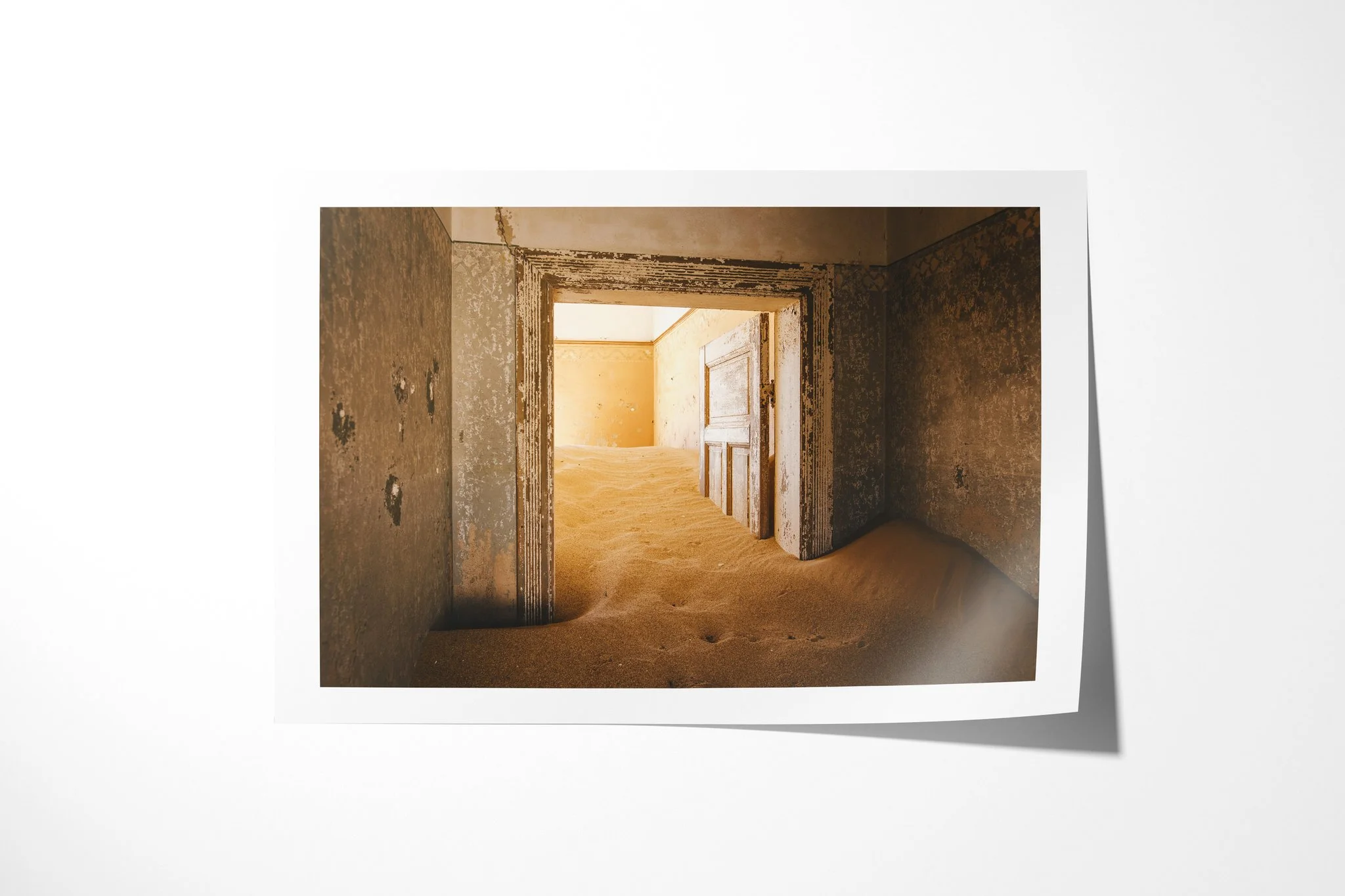 Doorway II presented as an unframed fine art paper print, depicting open doorways leading through worn ochre rooms whose floors are covered by rippled desert sand.