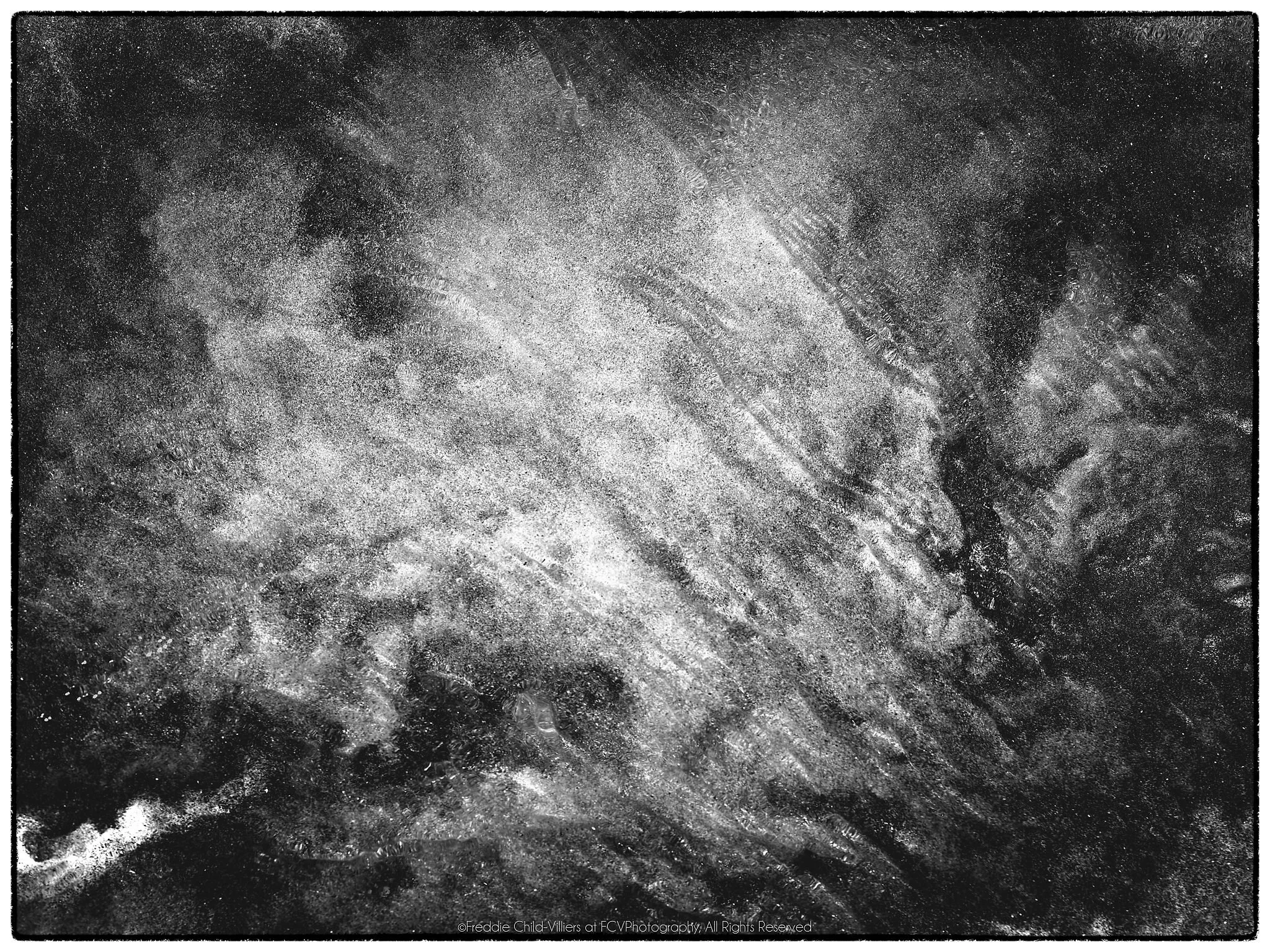 Pale diagonal sweep of layered streaks across a dark, clouded granular field.