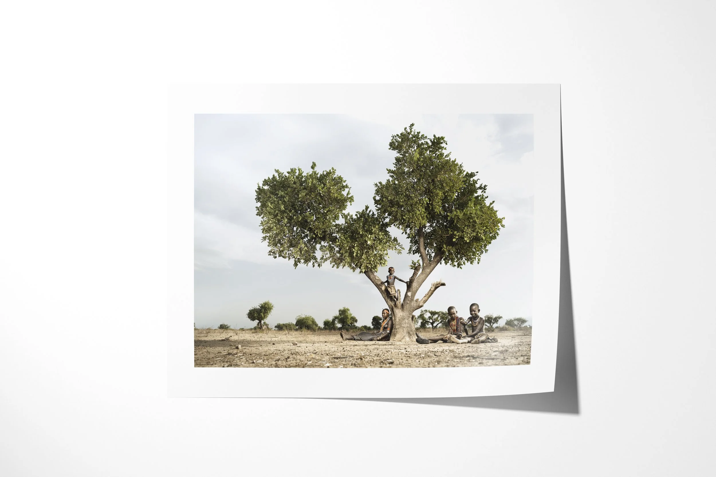 Fine art paper print of Kenina & her sisters, showing four Arbore sisters gathered beneath a broad tree, with one child perched in its branches.