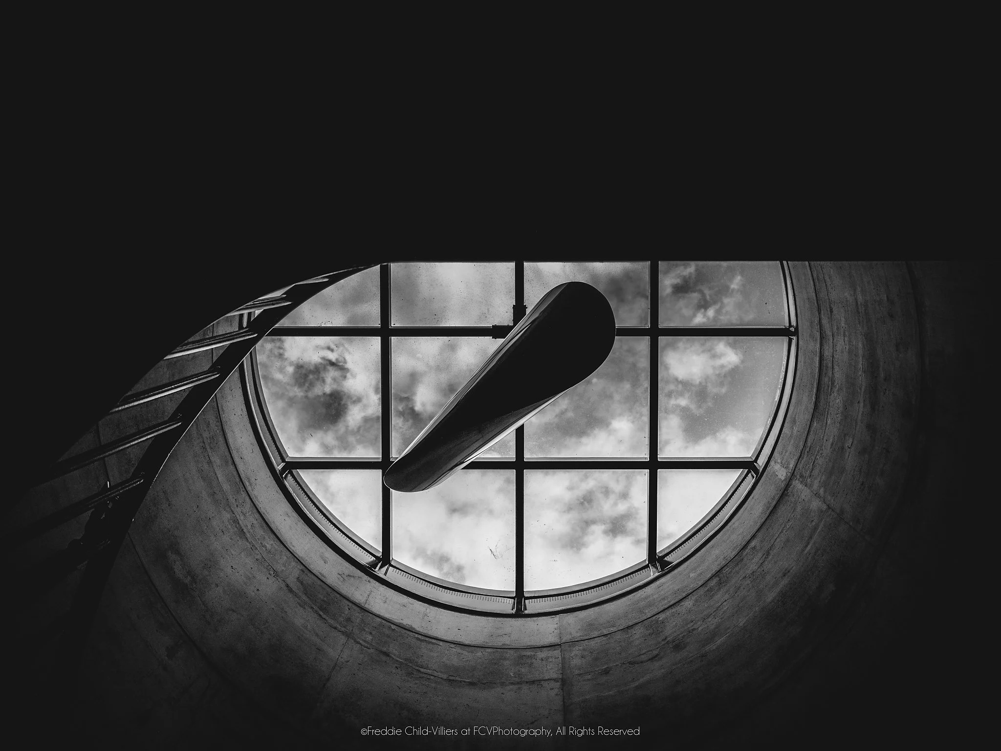 Circular concrete skylight with a window grid and clouds, crossed by two dark blade-like architectural forms.
