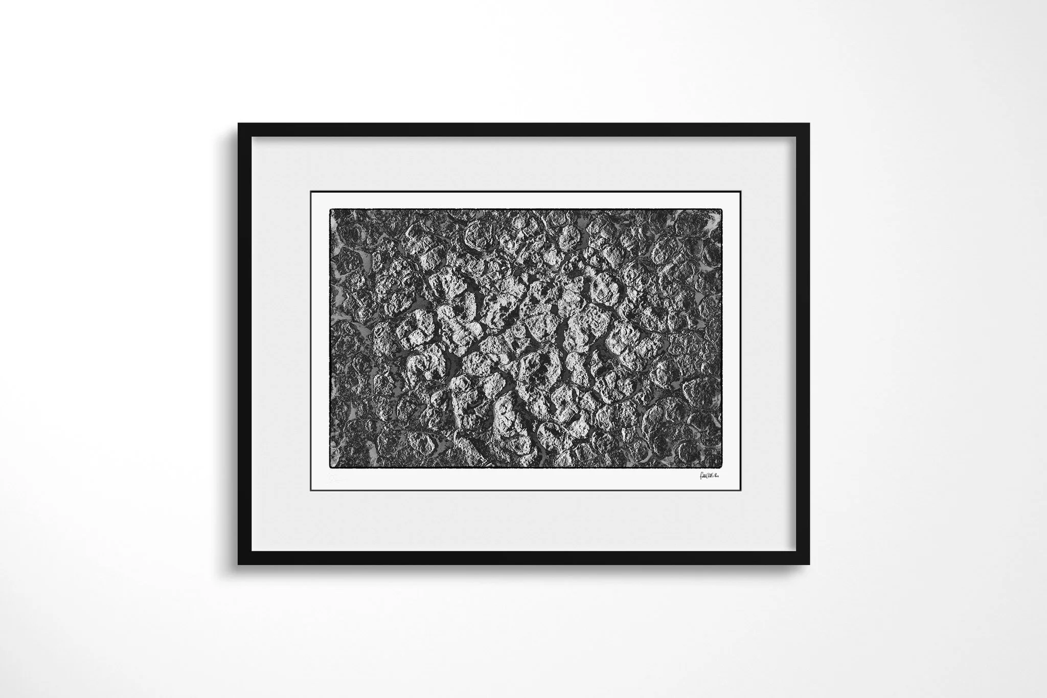 Black-framed presentation of Khamsin VI with a wide white mount, featuring repeating rounded cells of dried, fractured ground with raised edges and deep dark creases.
