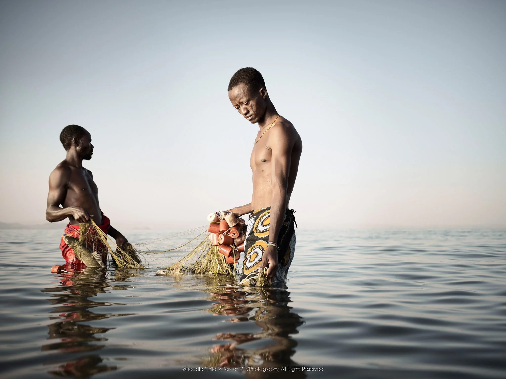 Jeremy & Zacheus, two El Molo fishermen wading in Lake Turkana as they retrieve a net.