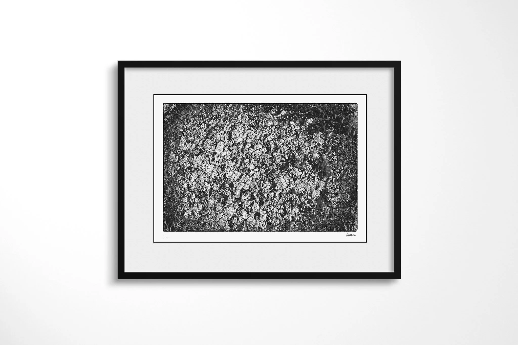 Framed presentation of Khamsin IV in a black frame with a wide white mount, showing a dense field of cracked ground fragments separated by dark irregular fissures.