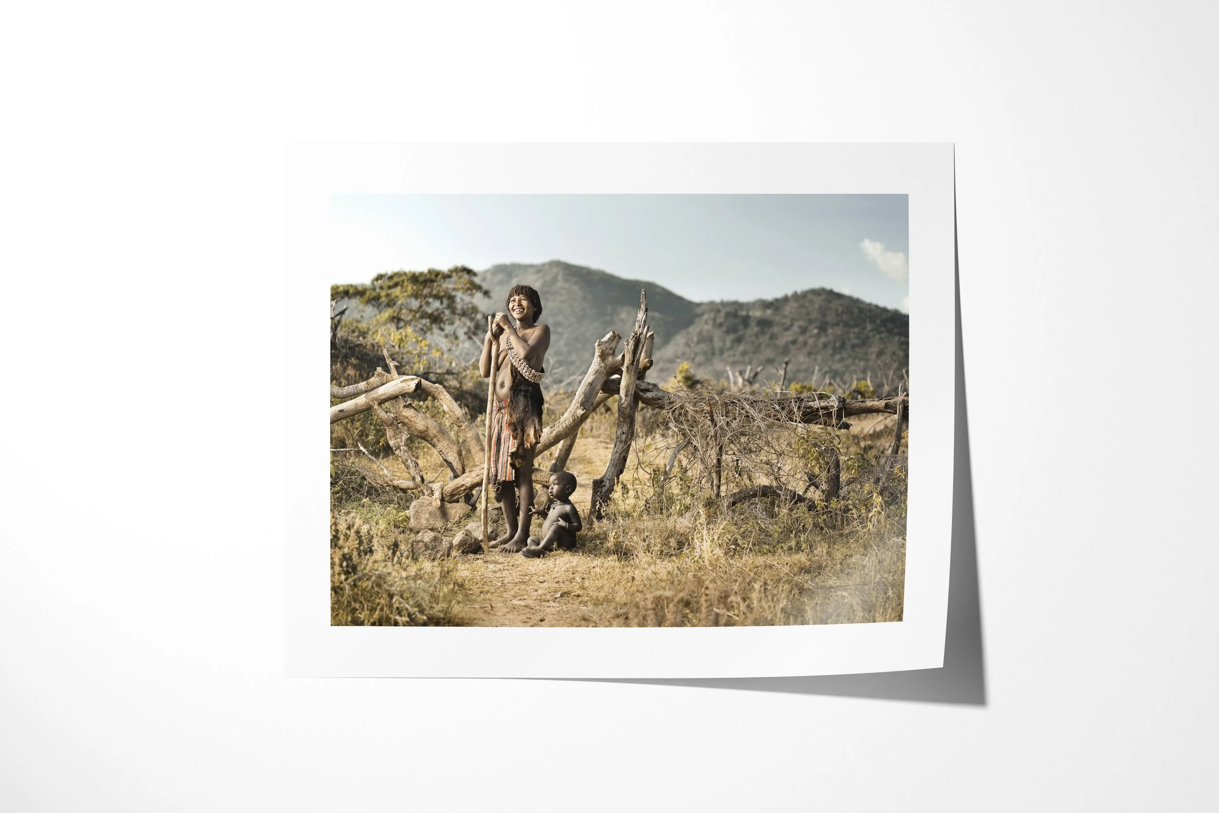 Fine art paper print of Sani & Mito, showing a Banna mother standing with a child beneath a tree while another child sits beside her.