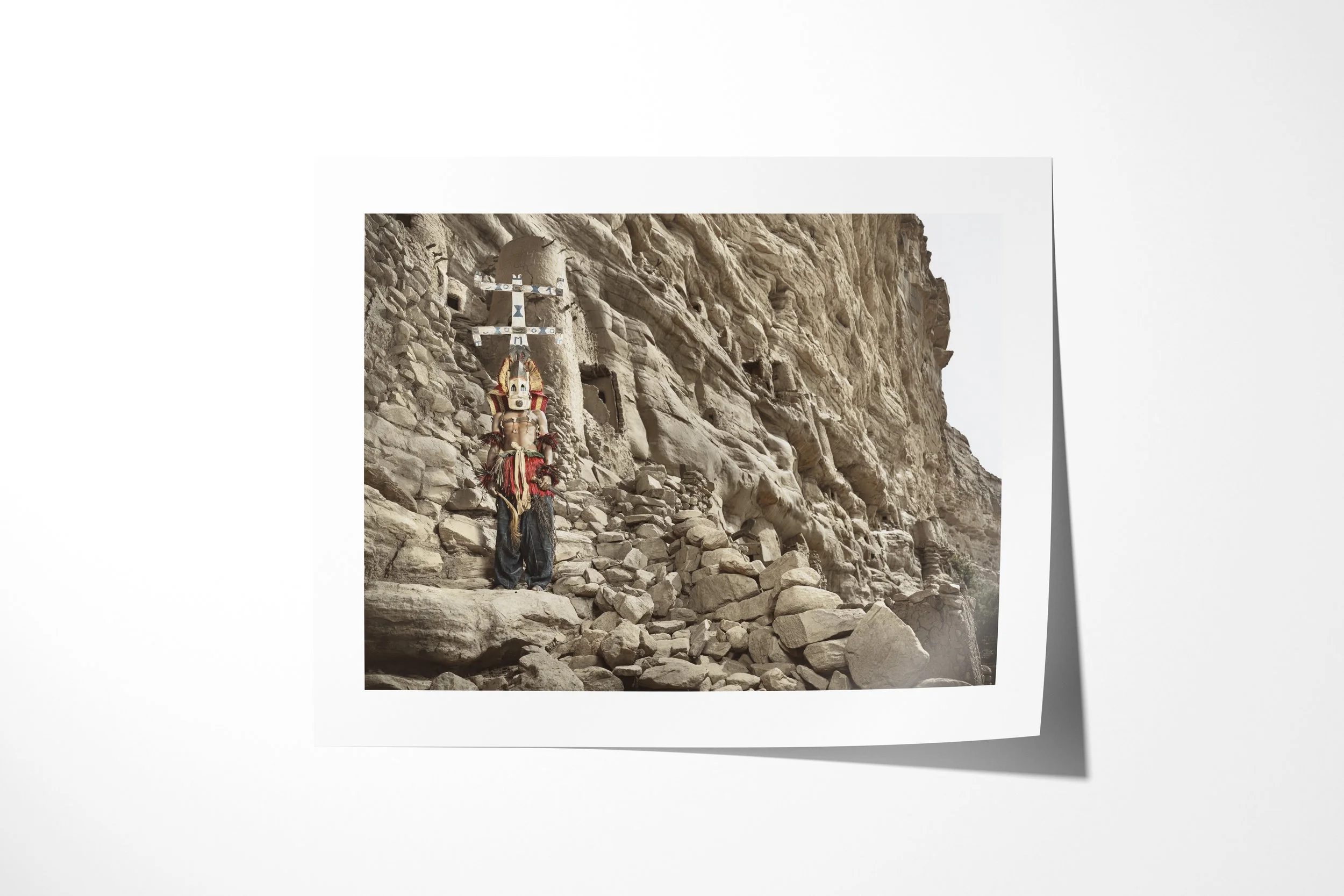 Fine art paper print of Kanaga (Mask), showing a Dogon Kanaga mask with a tall double-cross form standing below the Bandiagara cliffs.