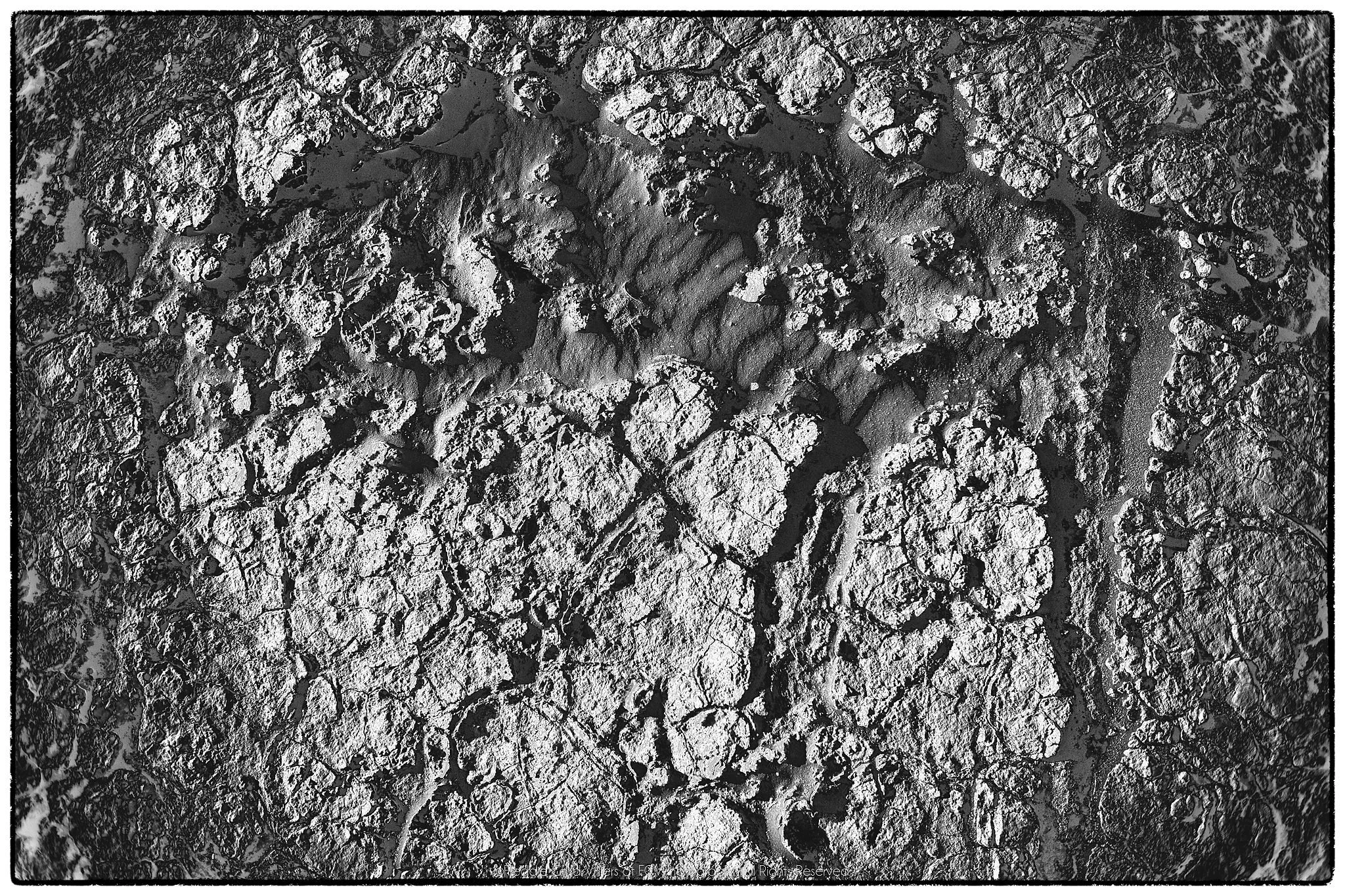Broken pale crust surrounding a smoother central opening of subtly rippled sand.