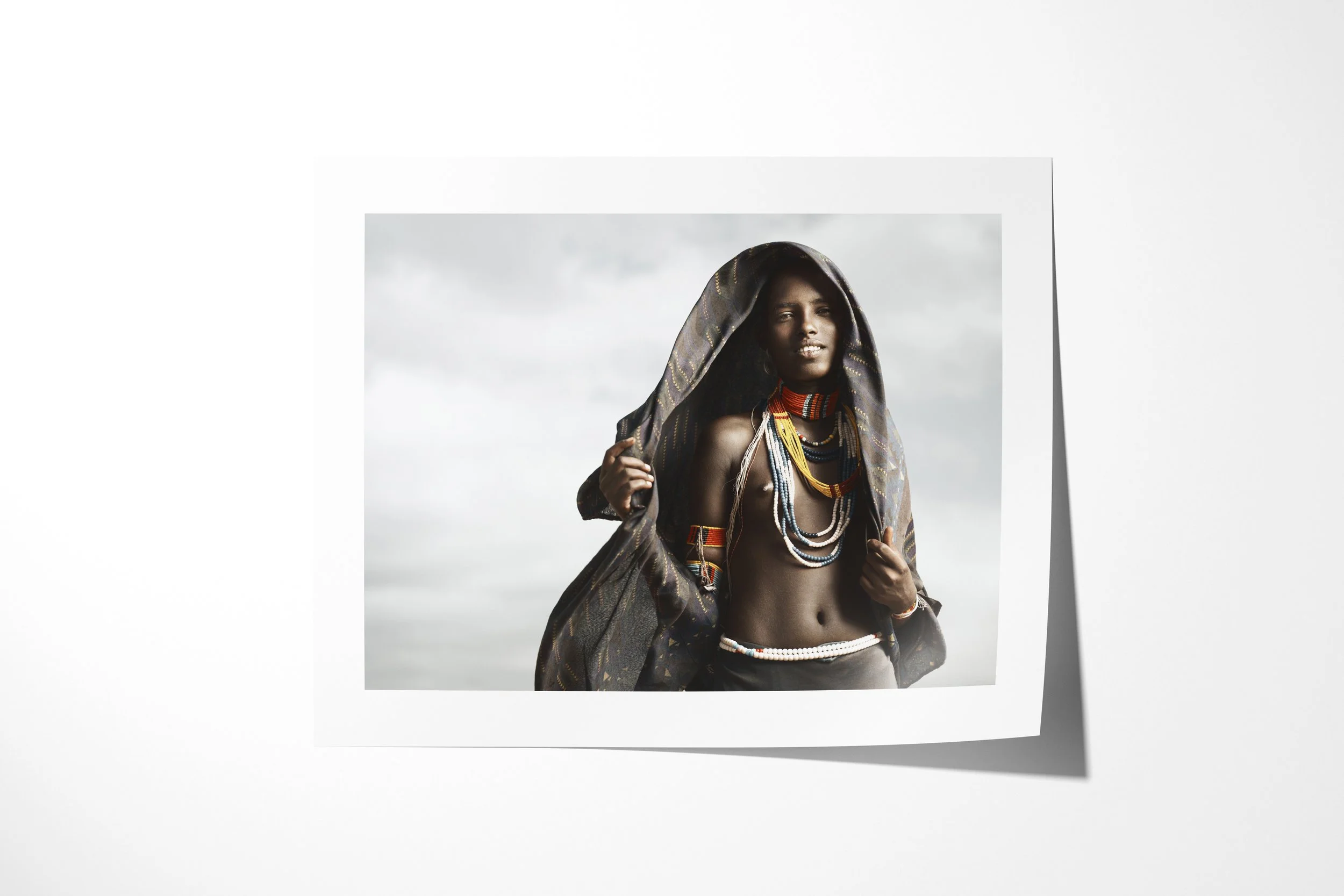 Fine art paper print of Hara, showing an unmarried Arbore woman wearing a dark head covering and layered coloured beadwork.