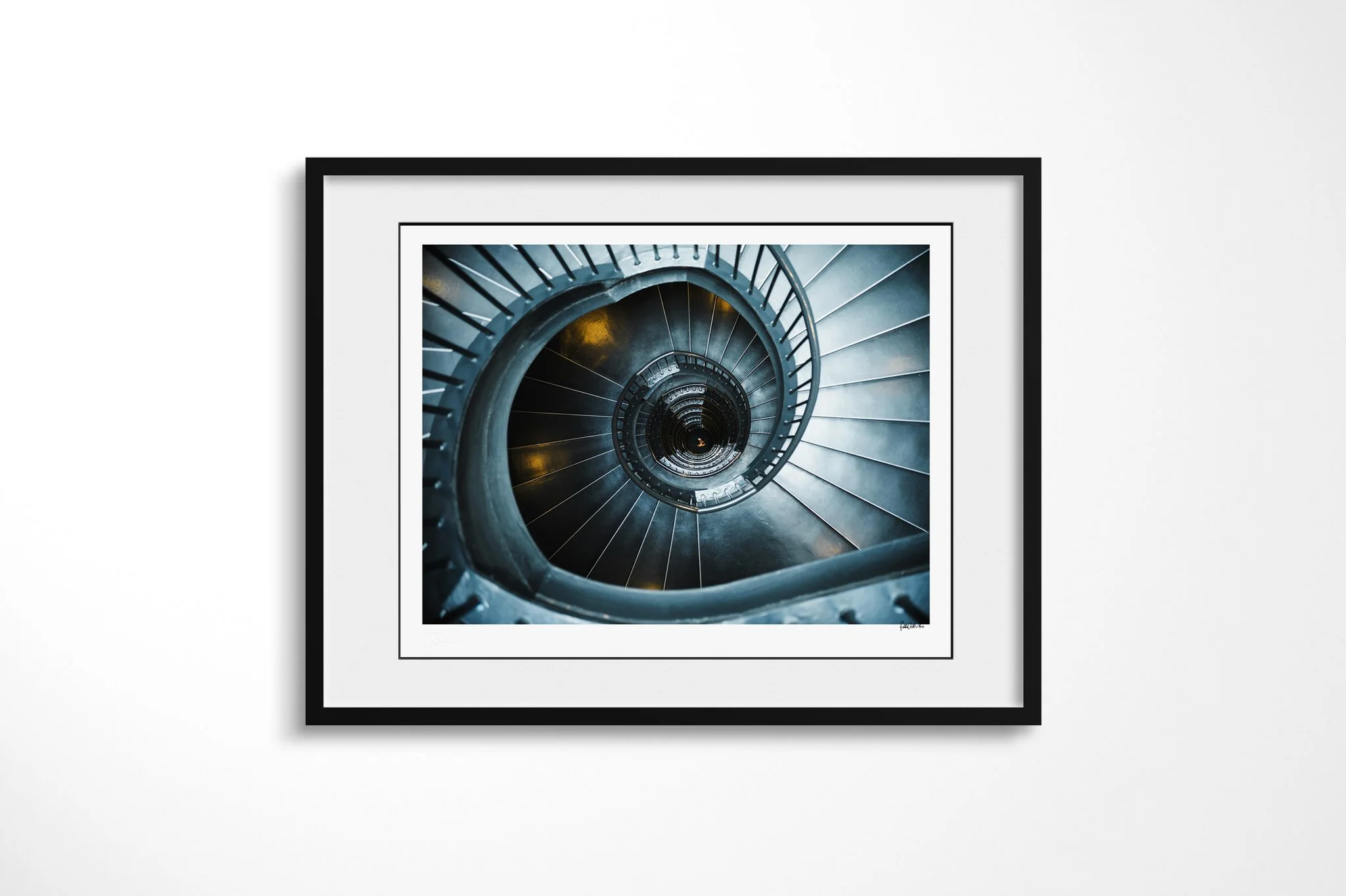 Spiral presented in a black frame with a white mount, depicting a teal-blue spiral staircase viewed from above, tightening around a deep central void with small amber lights.
