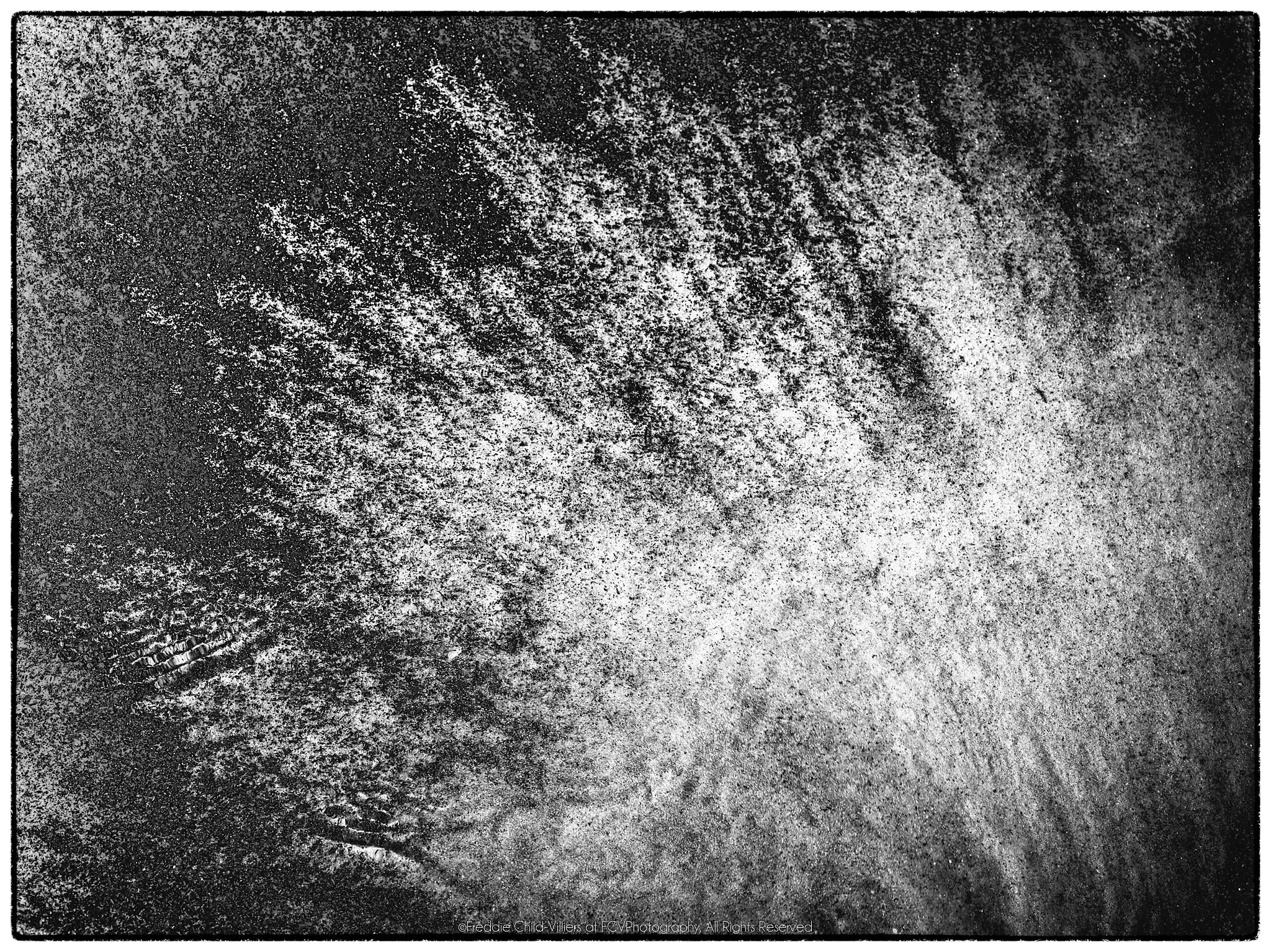 Bright fan of fine radiating streaks spreading diagonally across a dark granular surface.